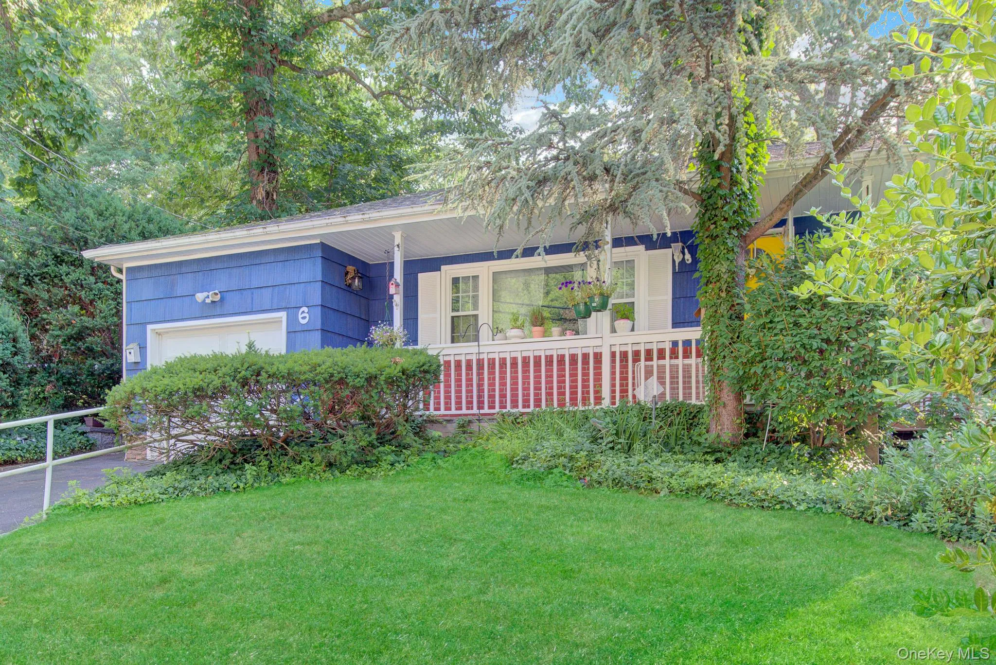 Blue siding exterior with white trim, a covered front porch featuring white railings over a brick base, and a one-car garage Blue siding exterior with white trim, a covered front porch featuring white railings over a brick base, and a one-car garage