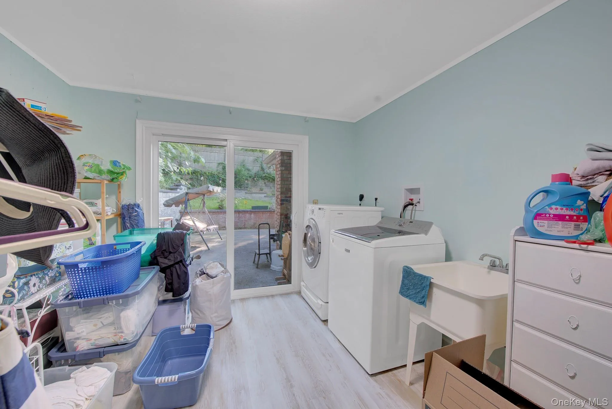 Utility room featuring wood-finish flooring, light blue walls, and a sliding glass door Utility room featuring wood-finish flooring, light blue walls, and a sliding glass door