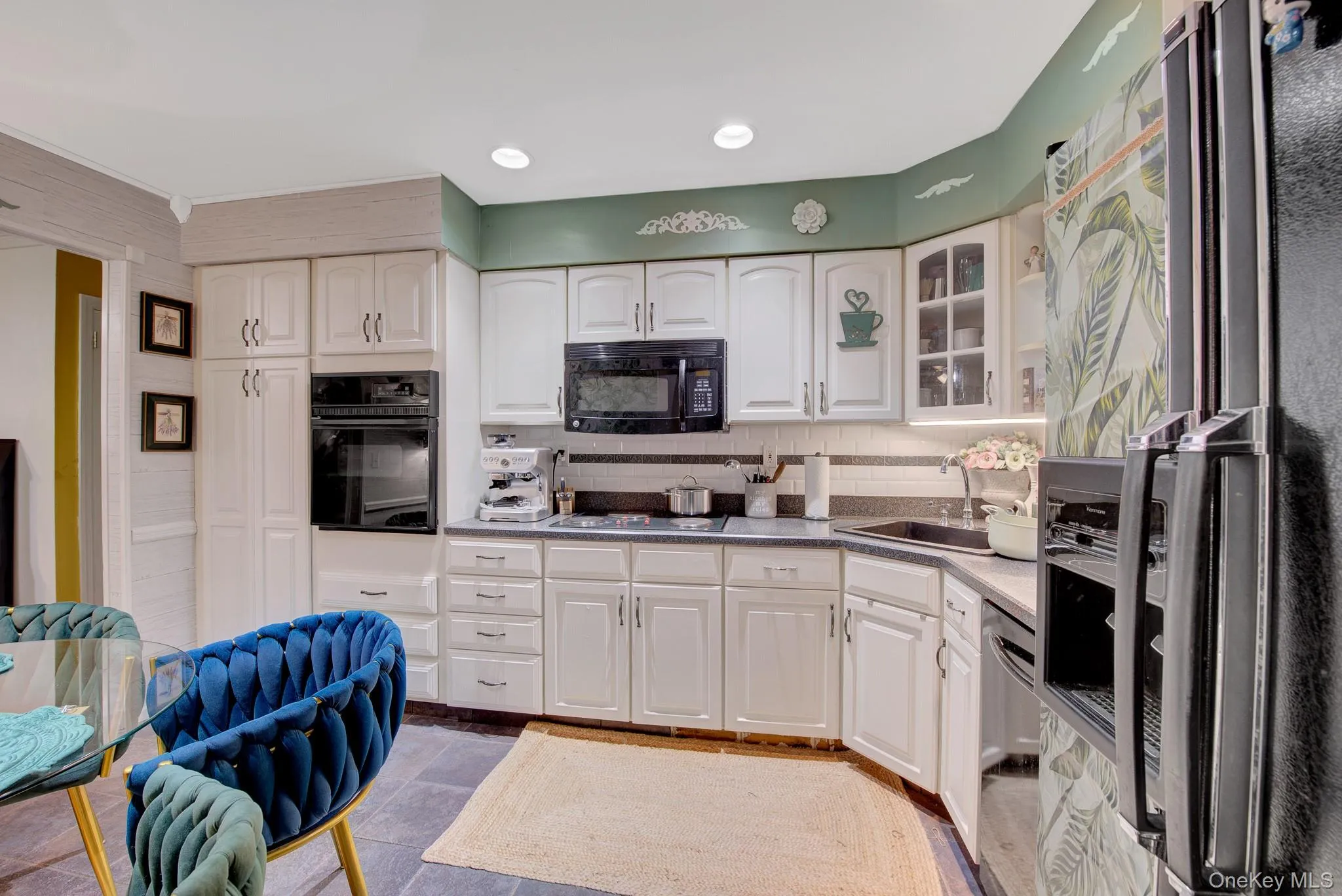 Kitchen featuring white cabinetry, integrated wall oven, built-in microwave, and black appliances Kitchen featuring white cabinetry, integrated wall oven, built-in microwave, and black appliances