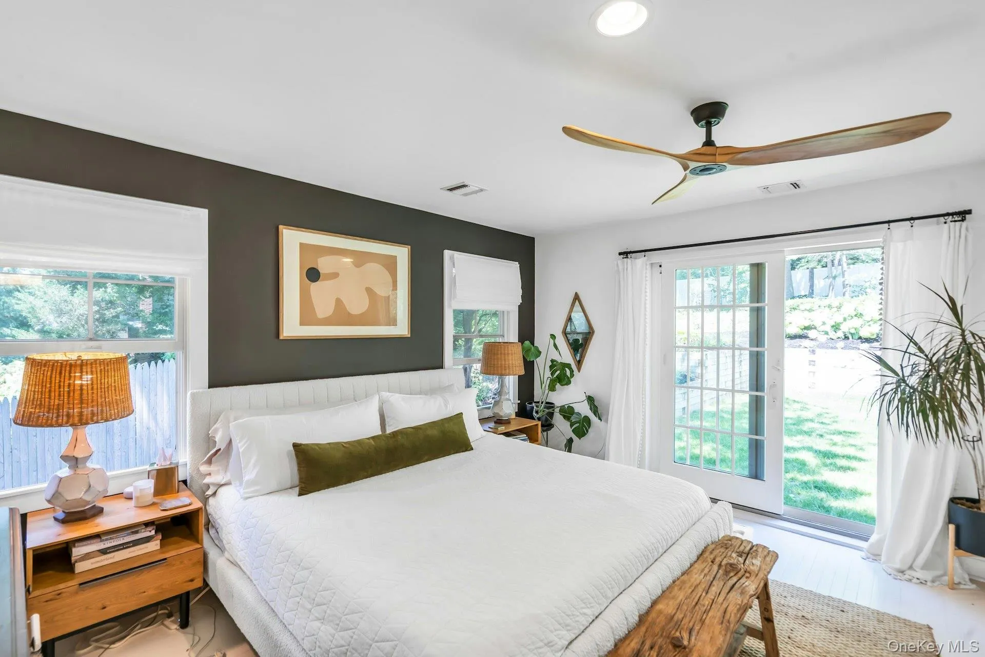 Primary bedroom with King bed featuring a dark accent wall, recessed lighting, and a modern ceiling fan with wood-finish blades Primary bedroom with King bed featuring a dark accent wall, recessed lighting, and a modern ceiling fan with wood-finish blades
