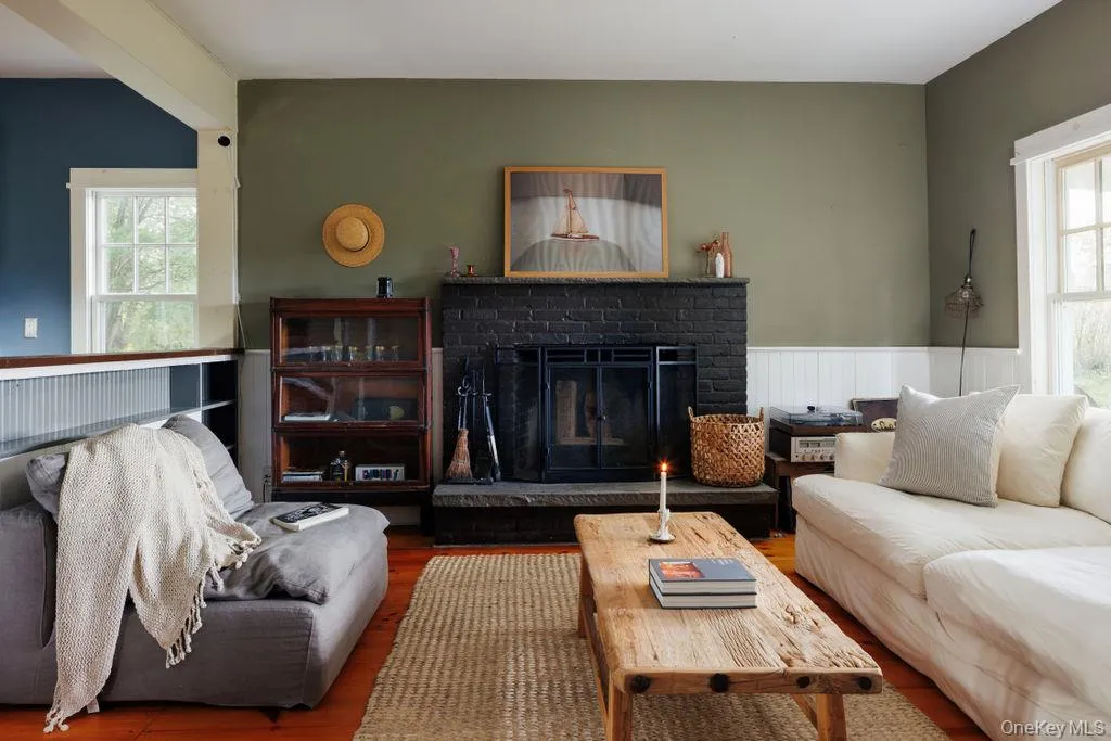 Living room featuring plenty of natural light, wood finished floors, a wainscoted wall, and a fireplace Living room featuring plenty of natural light, wood finished floors, a wainscoted wall, and a fireplace