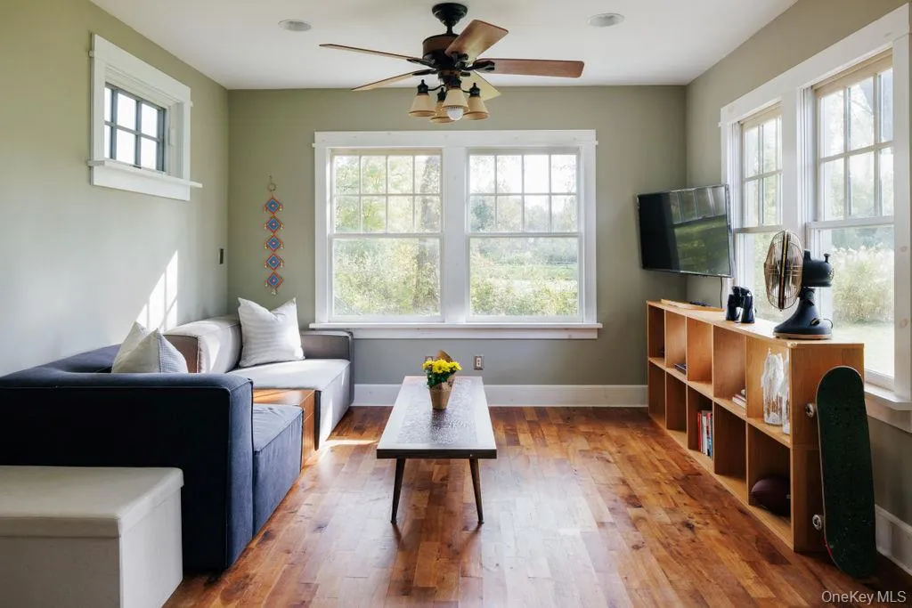 Sun room at rear of house featuring wood finished floors and a ceiling fan Sun room at rear of house featuring wood finished floors and a ceiling fan