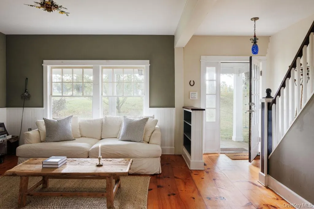 Living area with light wood-style floors, stairway, and wainscoting Living area with light wood-style floors, stairway, and wainscoting