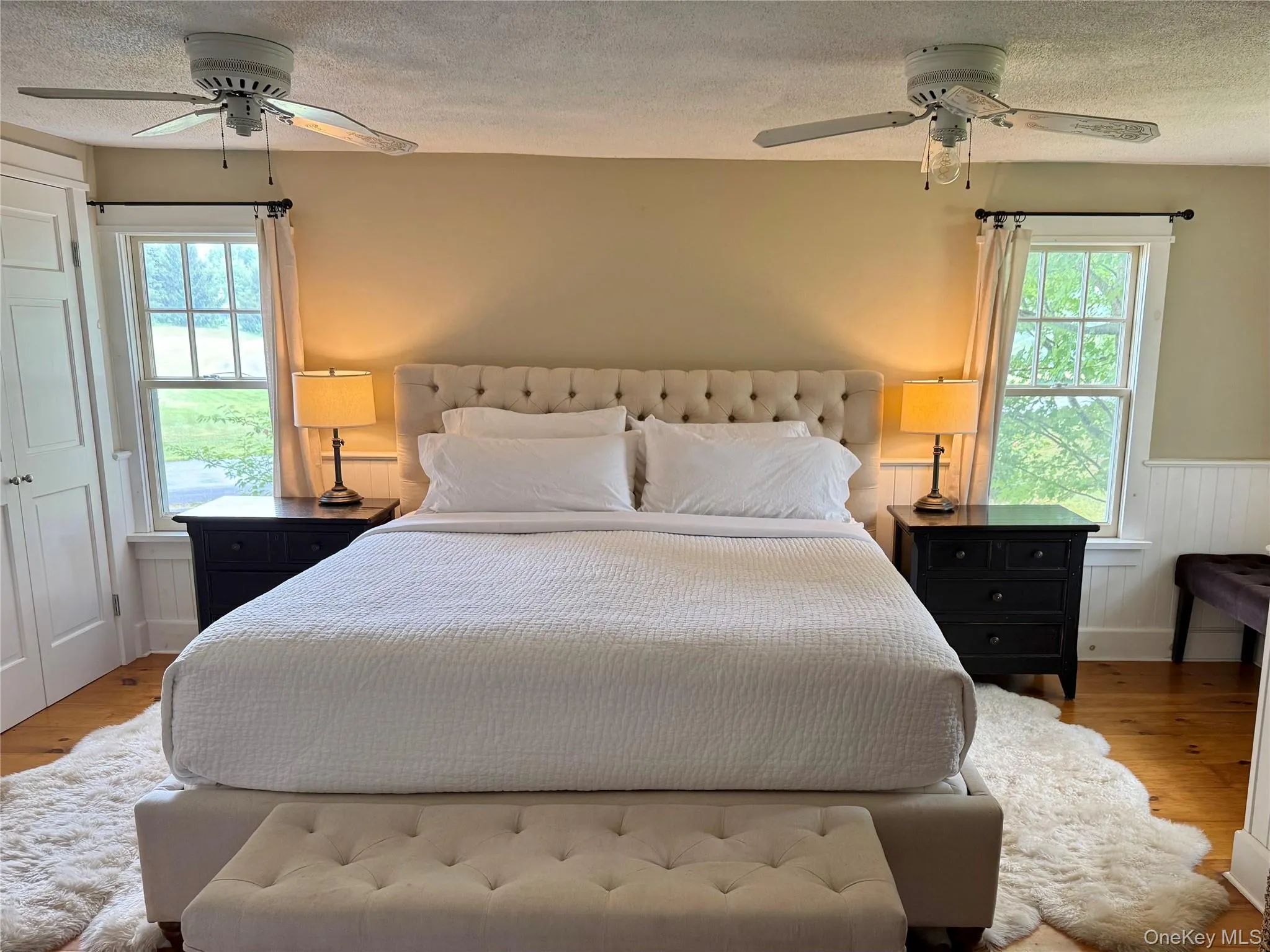 Bedroom featuring wood finished floors, a textured ceiling, a wainscoted wall, and ceiling fan Bedroom featuring wood finished floors, a textured ceiling, a wainscoted wall, and ceiling fan