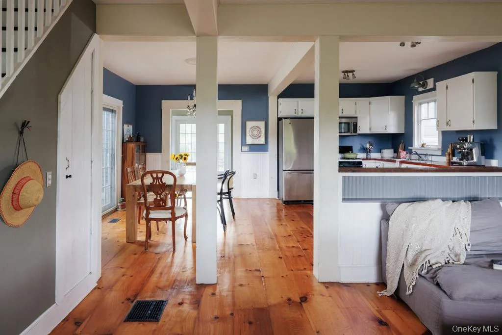 Kitchen featuring light wood-type flooring, appliances with stainless steel finishes, white cabinets, and a peninsula Kitchen featuring light wood-type flooring, appliances with stainless steel finishes, white cabinets, and a peninsula