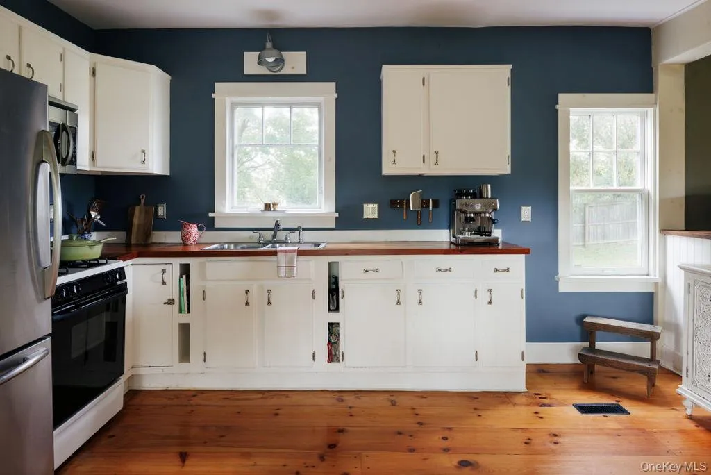 Kitchen featuring light wood-type flooring, stainless steel appliances, and white cabinetry Kitchen featuring light wood-type flooring, stainless steel appliances, and white cabinetry