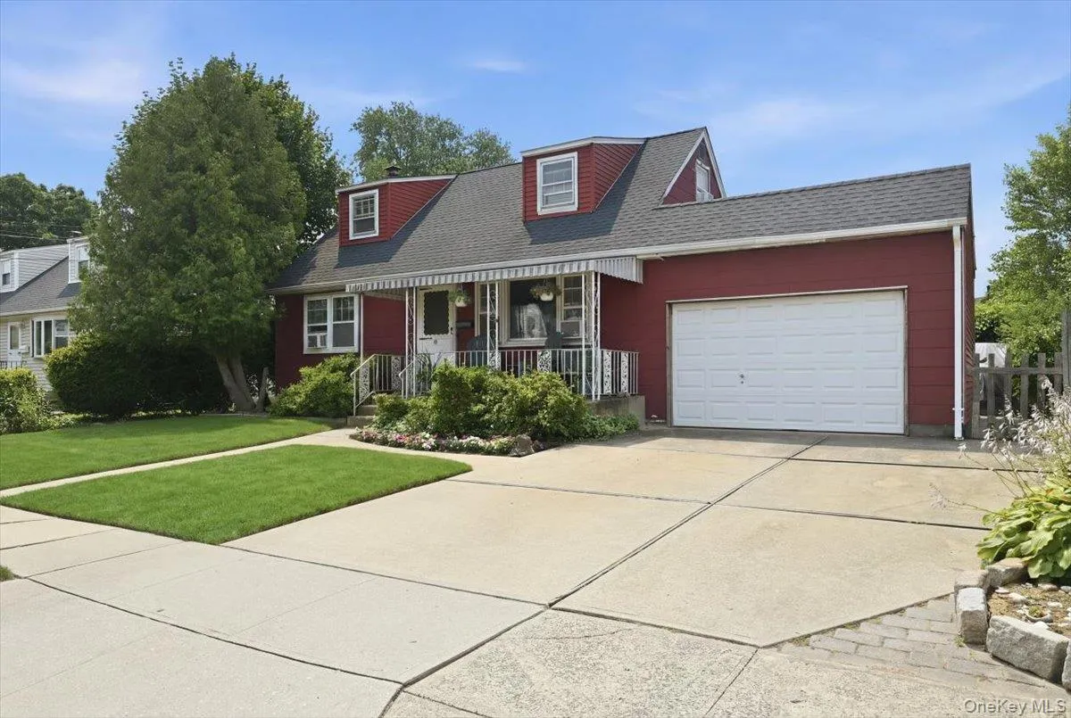 Red-sided residence featuring a dormered roofline and an attached single-car garage Red-sided residence featuring a dormered roofline and an attached single-car garage