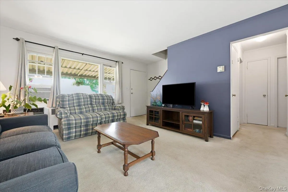 Living area featuring light-toned carpeting and a contrasting accent wall Living area featuring light-toned carpeting and a contrasting accent wall