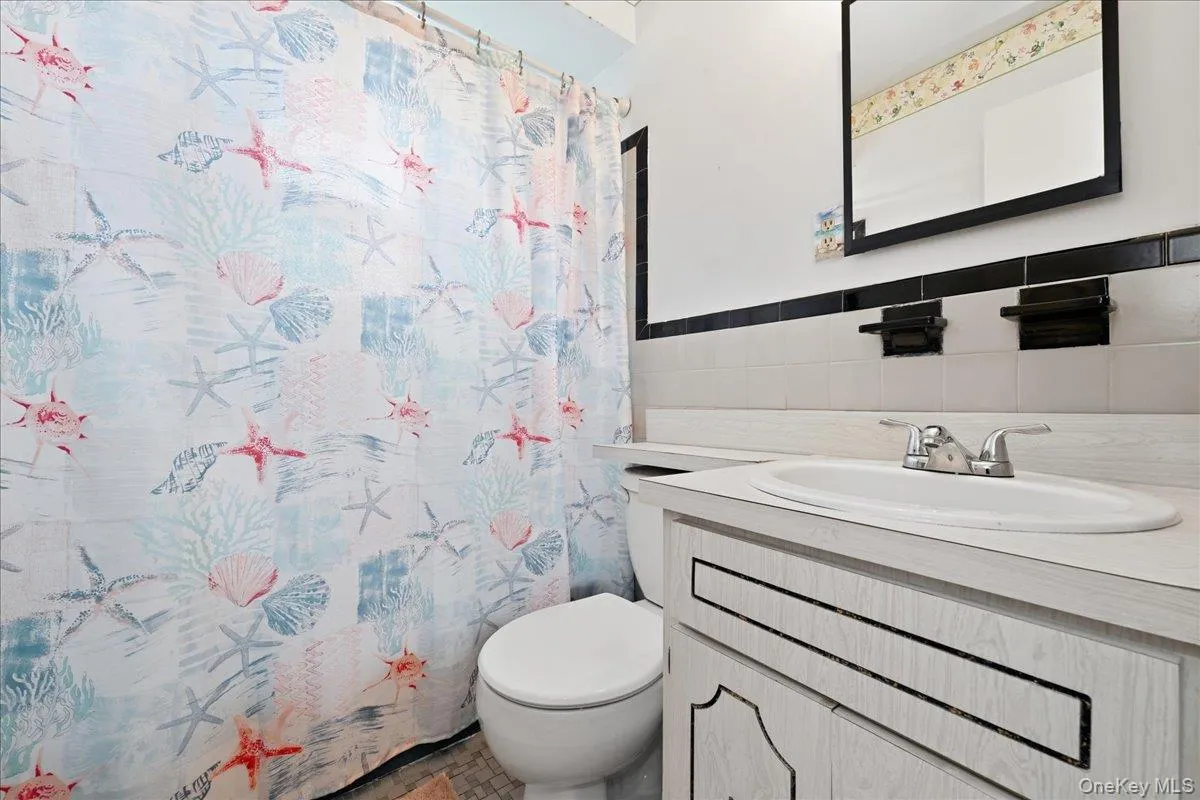 Bathroom featuring a white vanity with an integrated sink, dual-handle faucet, and a wall-mounted framed mirror Bathroom featuring a white vanity with an integrated sink, dual-handle faucet, and a wall-mounted framed mirror