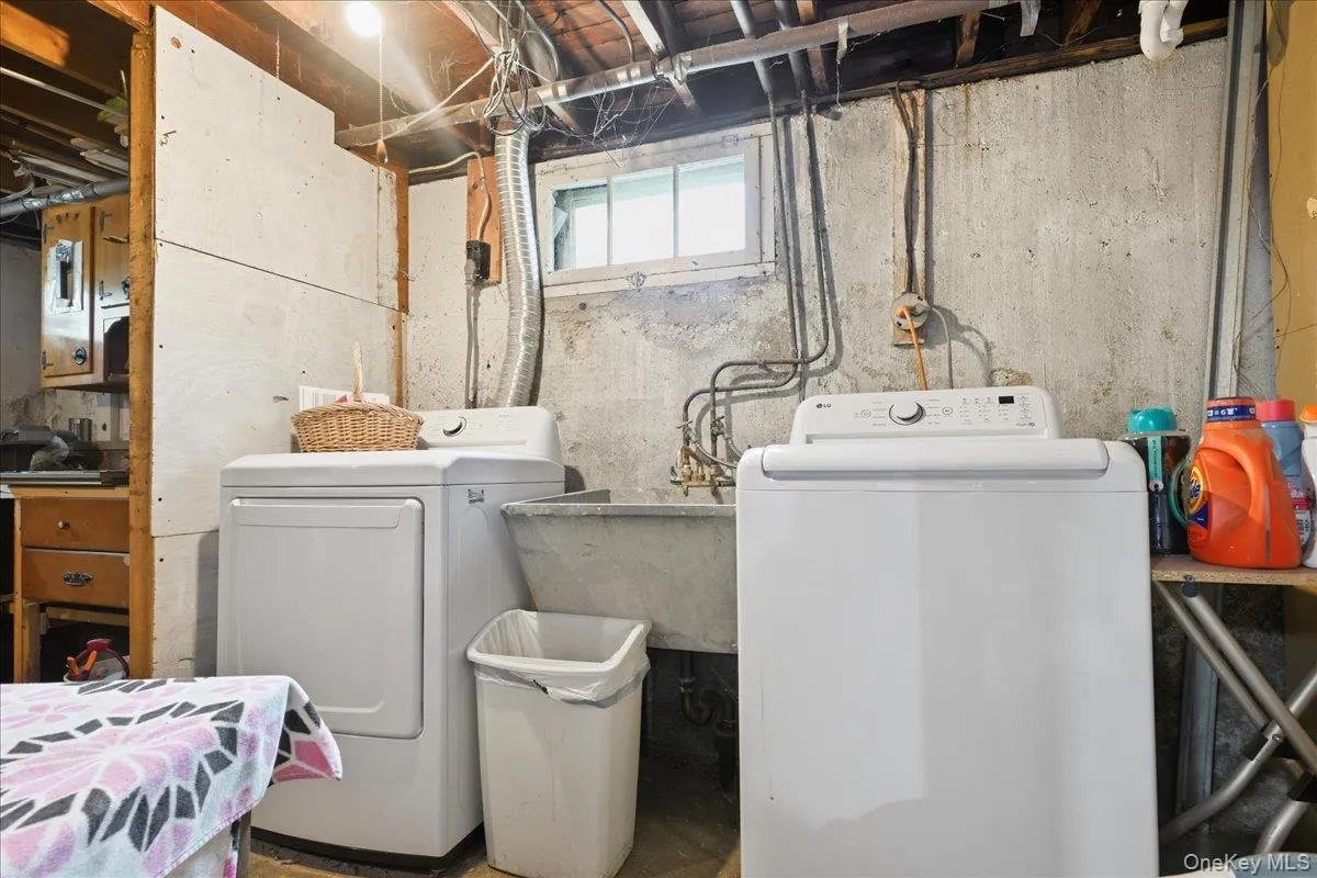 Laundry area featuring a utility sink, exposed ceiling joists, and a window providing natural light Laundry area featuring a utility sink, exposed ceiling joists, and a window providing natural light