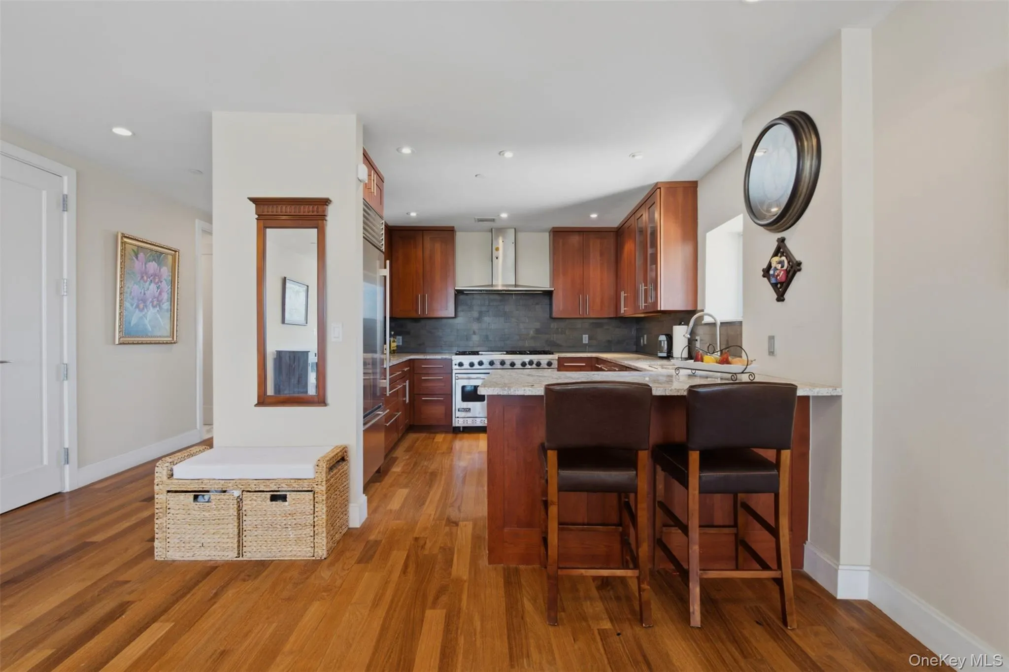 Modern kitchen featuring wood-finish flooring, recessed lighting, and stainless steel appliances Modern kitchen featuring wood-finish flooring, recessed lighting, and stainless steel appliances