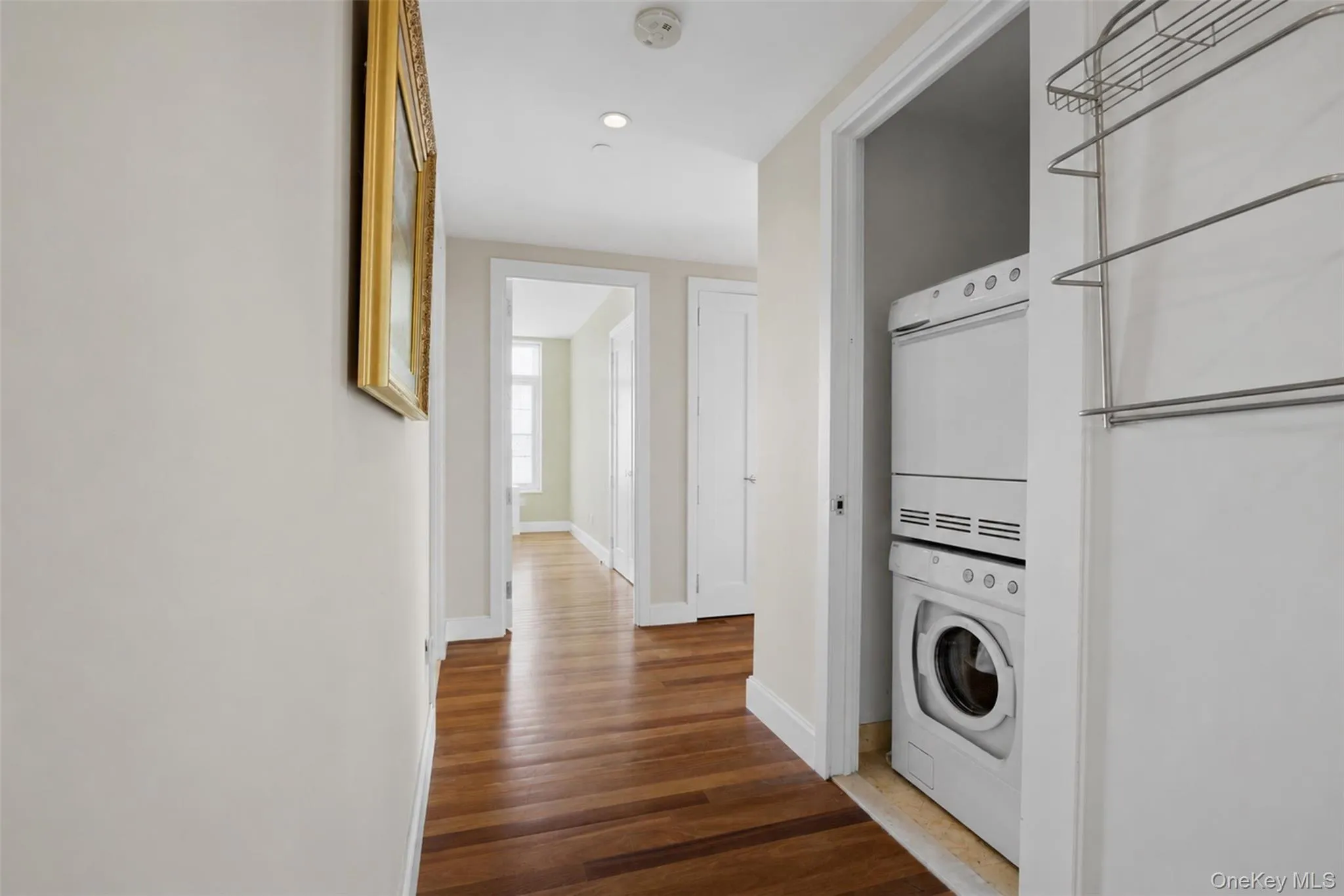 Hallway featuring wood-finish flooring, recessed lighting, and white baseboards Hallway featuring wood-finish flooring, recessed lighting, and white baseboards