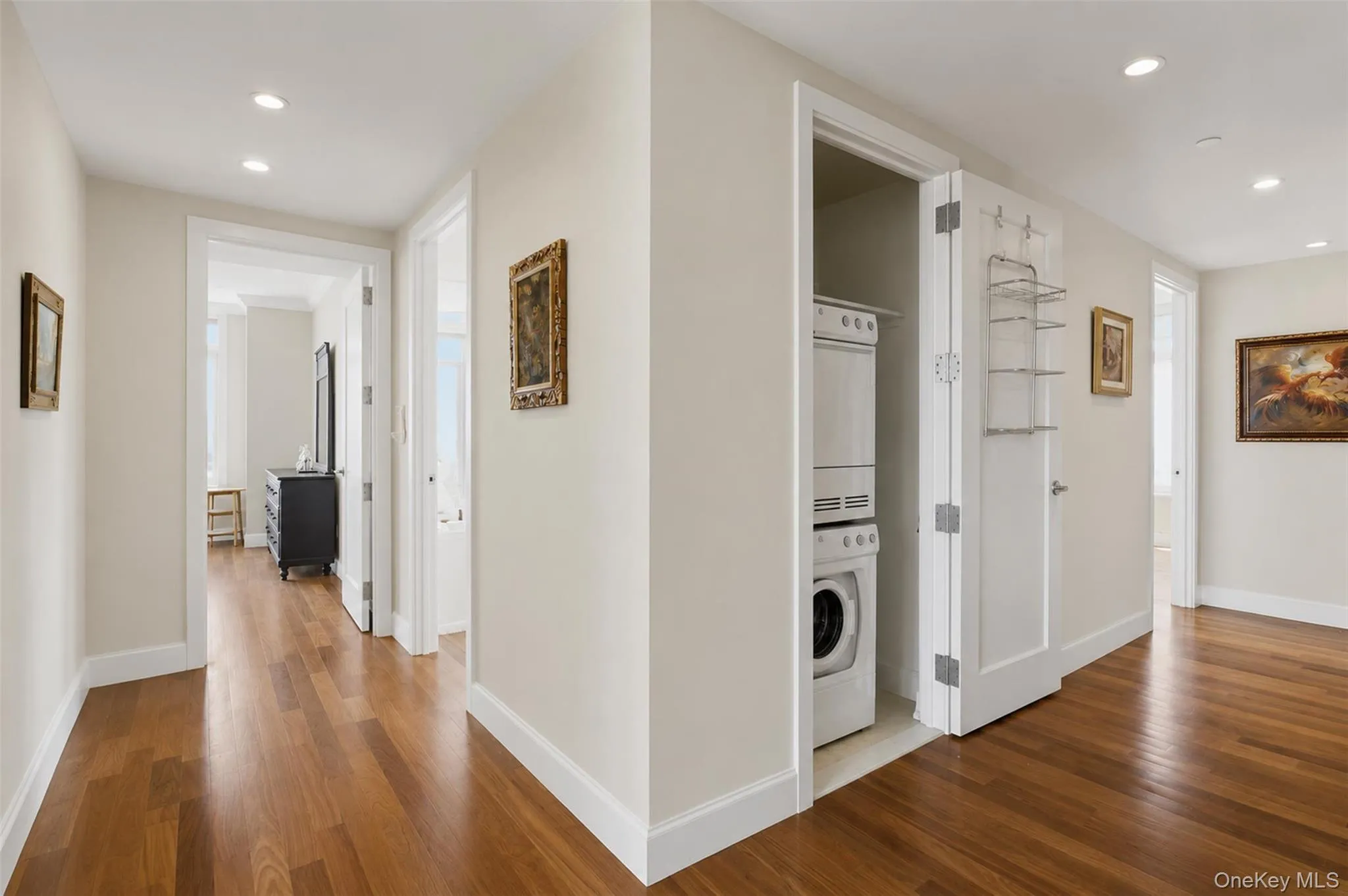 Hallway featuring wood-finish flooring, recessed lighting, and a stacked washer and dryer unit Hallway featuring wood-finish flooring, recessed lighting, and a stacked washer and dryer unit