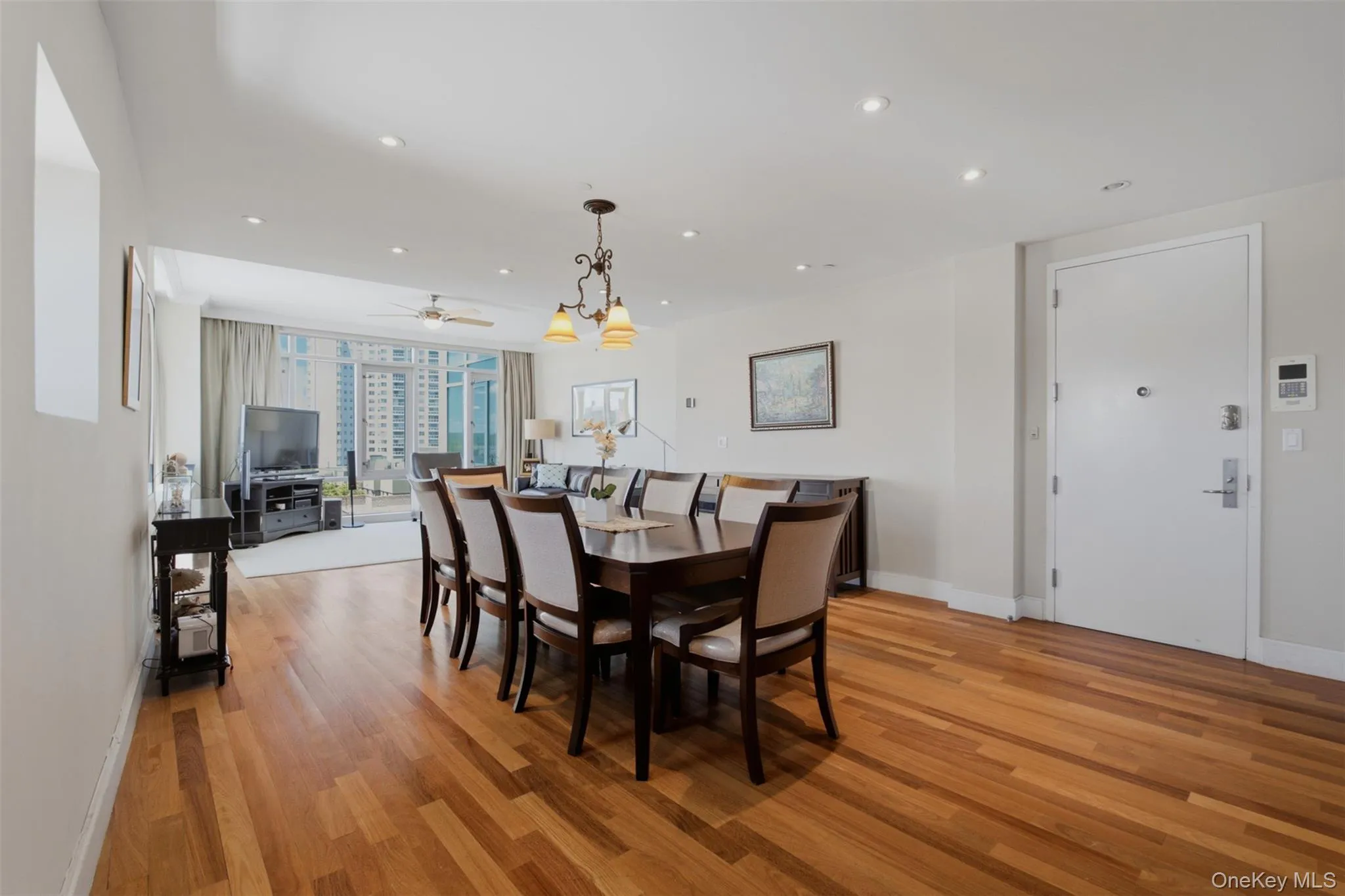 Open-concept living area featuring wood-finish flooring, recessed lighting, and a chandelier Open-concept living area featuring wood-finish flooring, recessed lighting, and a chandelier