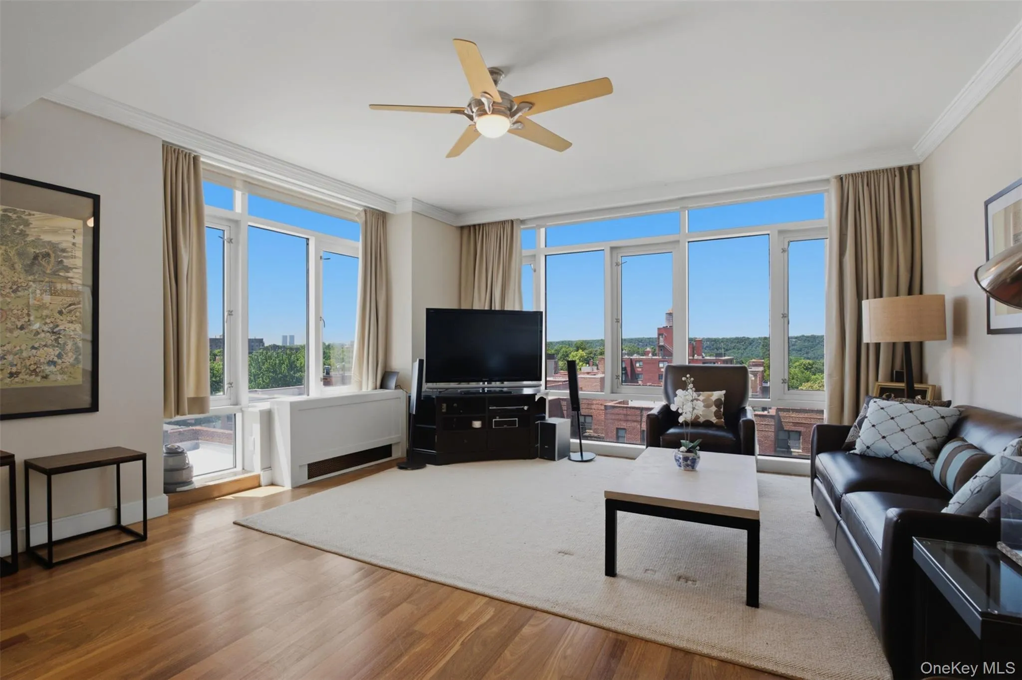Expansive living area with wood-finish flooring and large windows Expansive living area with wood-finish flooring and large windows
