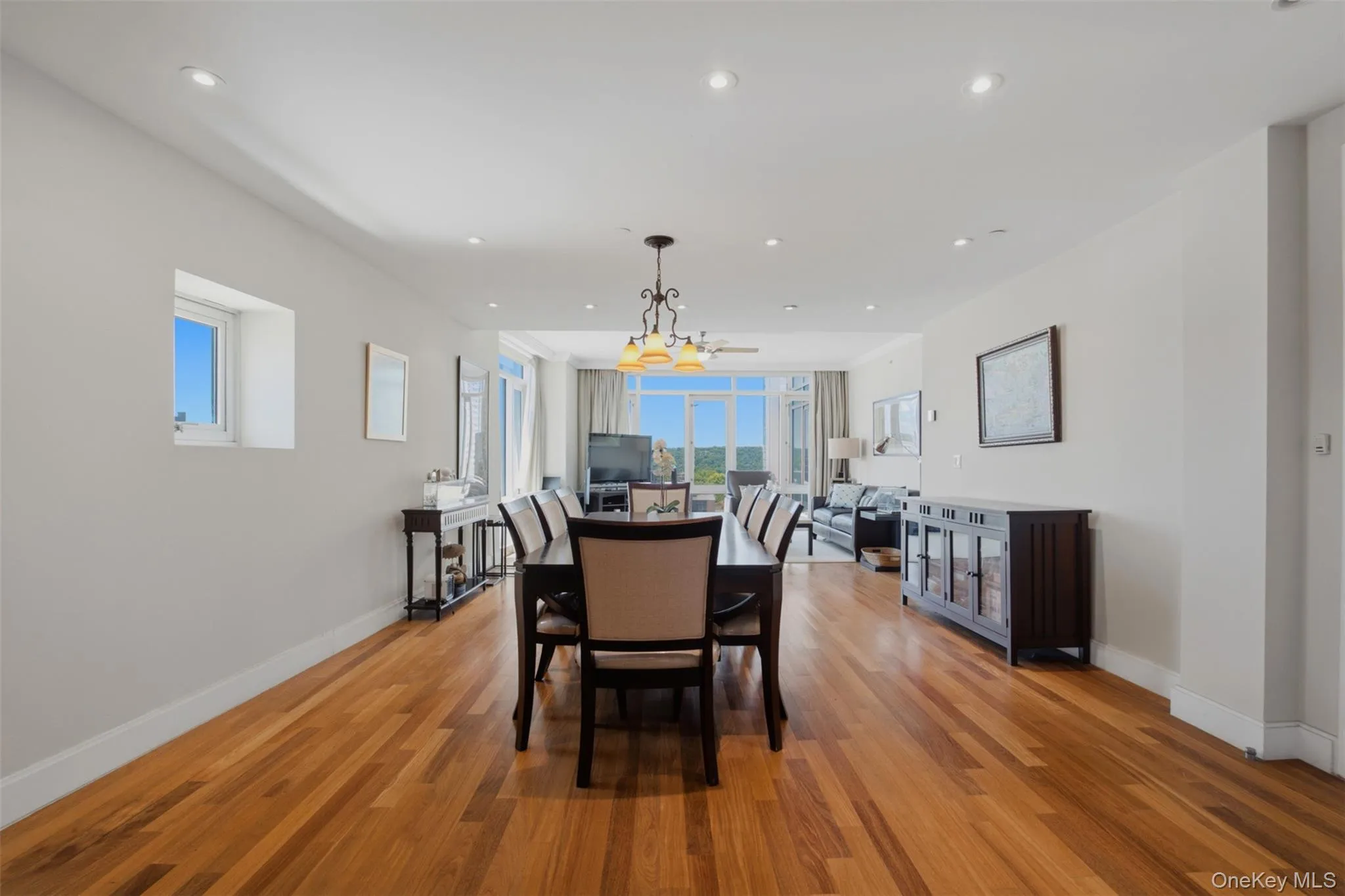 Open-concept living area featuring wood-finish flooring, recessed lighting, and expansive windows Open-concept living area featuring wood-finish flooring, recessed lighting, and expansive windows