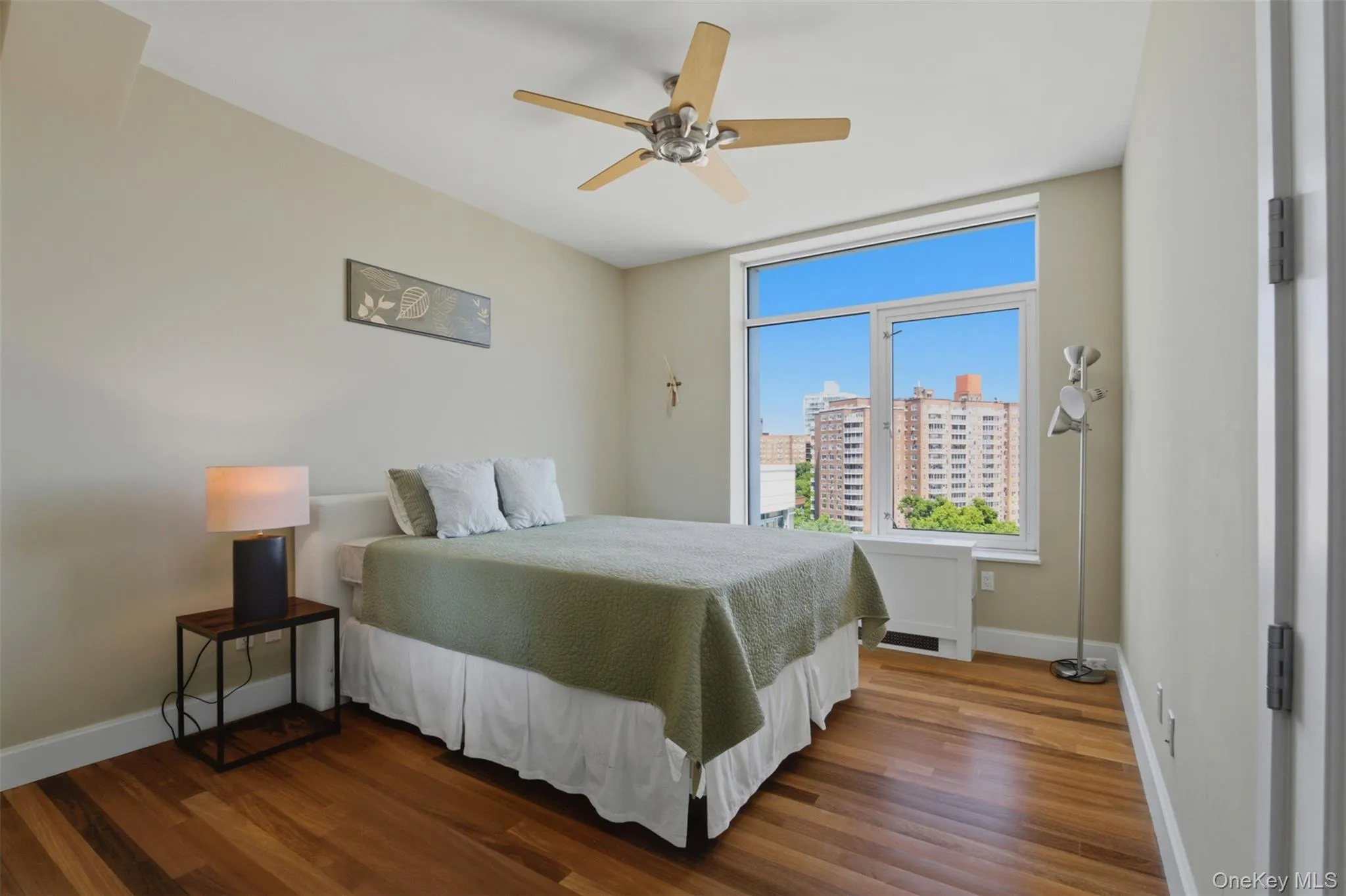 Bedroom 3 featuring wood-finish flooring, a contemporary ceiling fan, and a large window offering urban building views Bedroom 3 featuring wood-finish flooring, a contemporary ceiling fan, and a large window offering urban building views