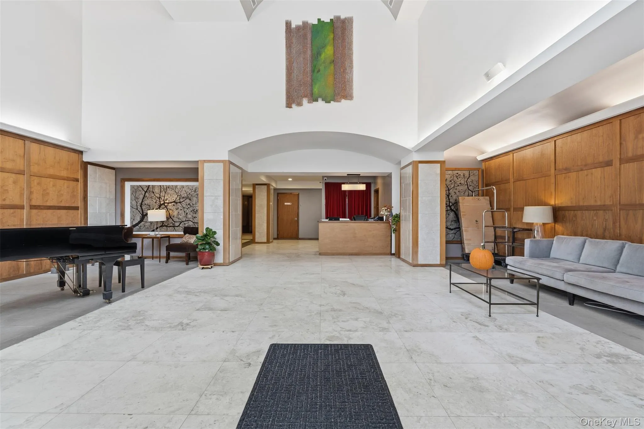 Spacious lobby with light-toned tile flooring and wood paneling Spacious lobby with light-toned tile flooring and wood paneling