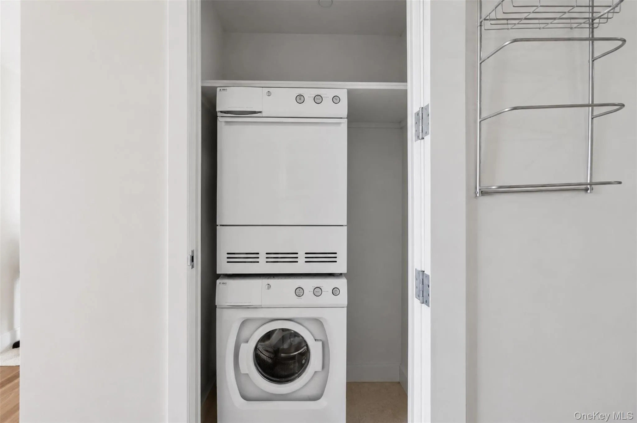 Dedicated laundry closet featuring a stacked white washer and dryer unit Dedicated laundry closet featuring a stacked white washer and dryer unit