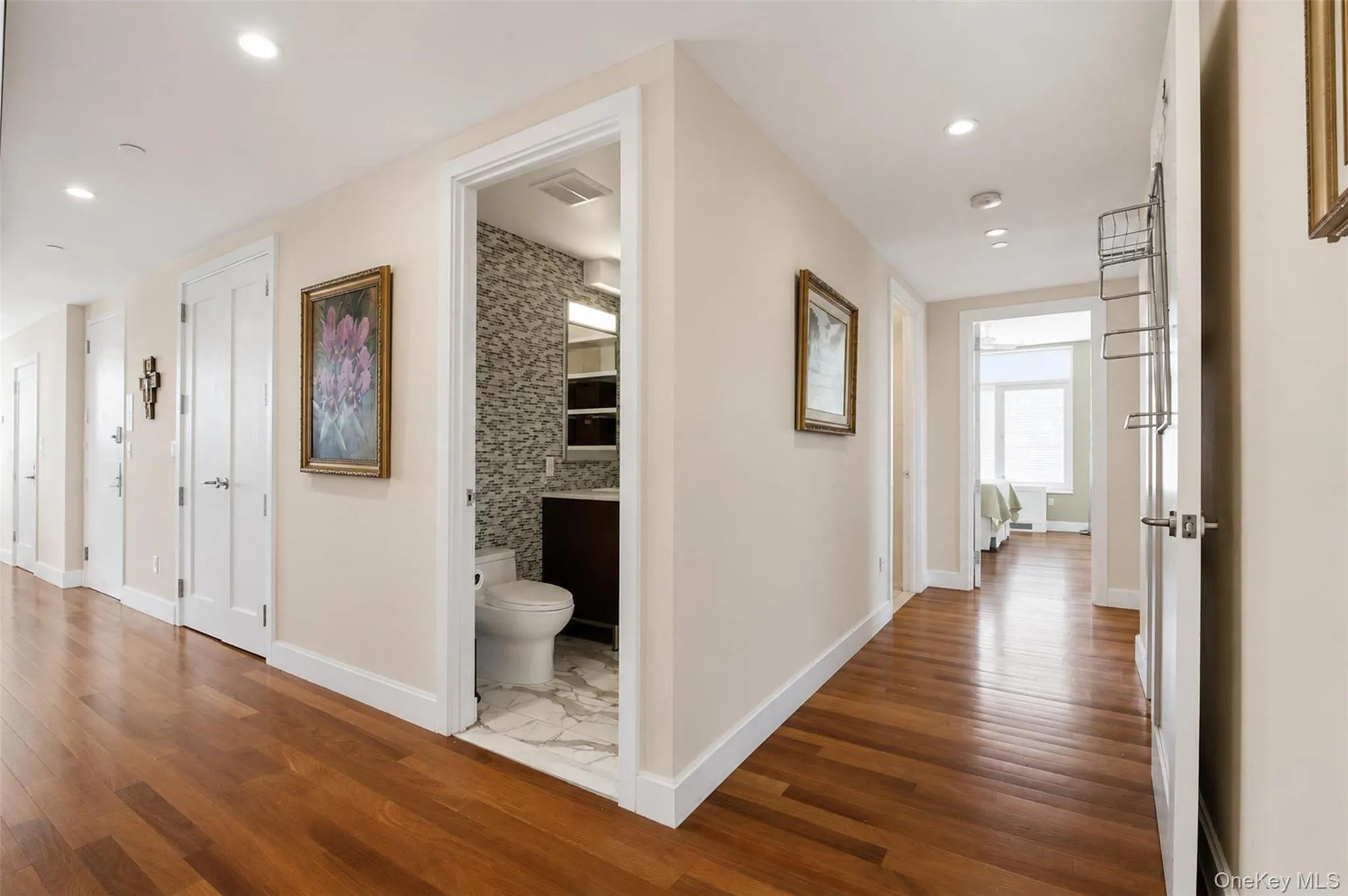 Hardwood flooring extends throughout this interior hallway, featuring recessed lighting and a white trim package Hardwood flooring extends throughout this interior hallway, featuring recessed lighting and a white trim package