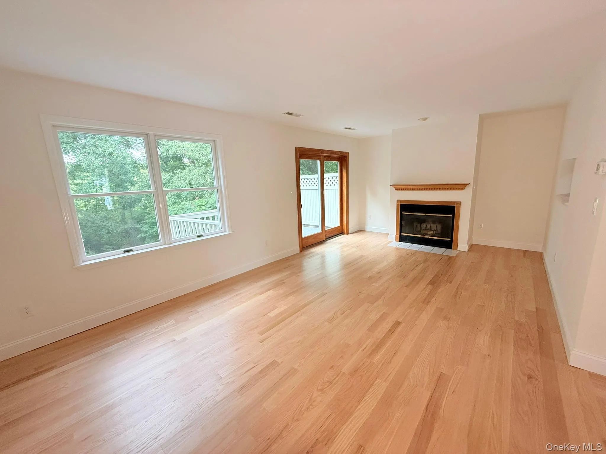 A bright and inviting living room designed for comfort and everyday living. The fireplace creates a warm focal point, while large windows bring in natural light A bright and inviting living room designed for comfort and everyday living. The fireplace creates a warm focal point, while large windows bring in natural light