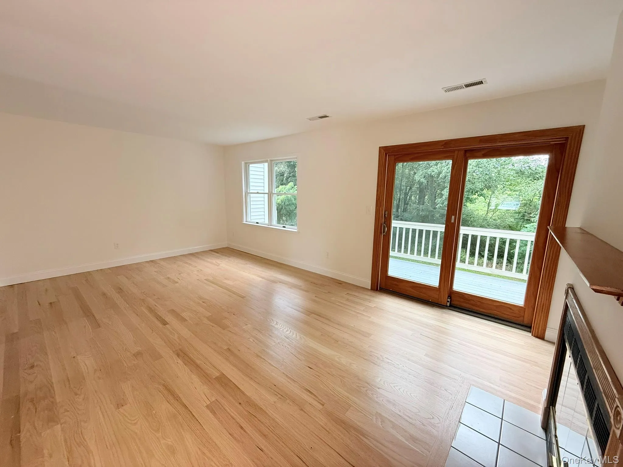 Living room with sliding glass doors leading to a private deck overlooking the wooded setting. Living room with sliding glass doors leading to a private deck overlooking the wooded setting.