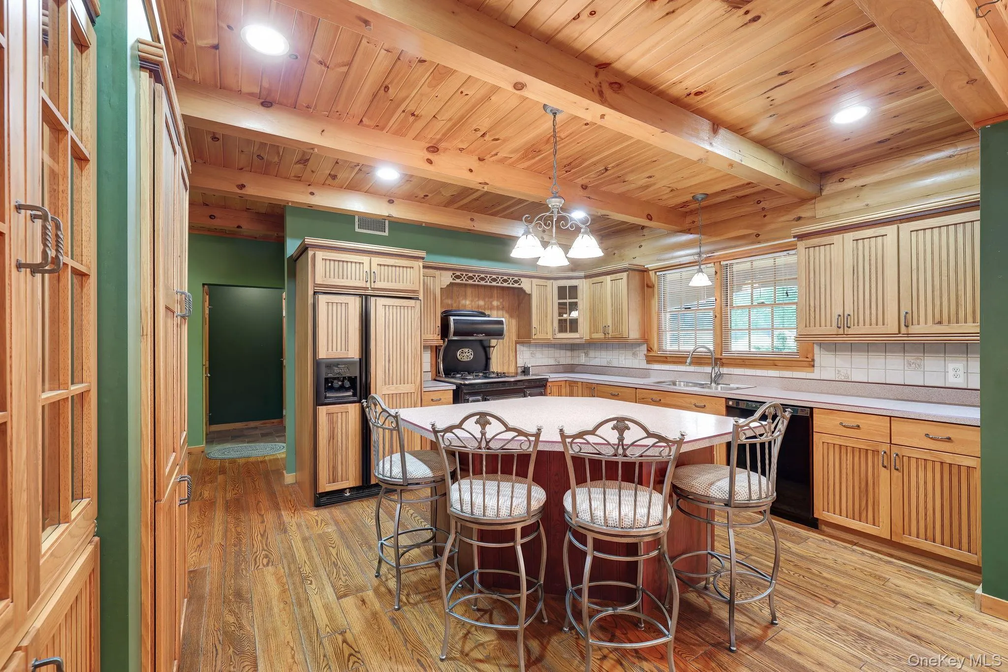 Kitchen featuring a multi-sided island with seating, exposed wood beam ceiling, light wood cabinetry, and recessed lighting. Kitchen featuring a multi-sided island with seating, exposed wood beam ceiling, light wood cabinetry, and recessed lighting.