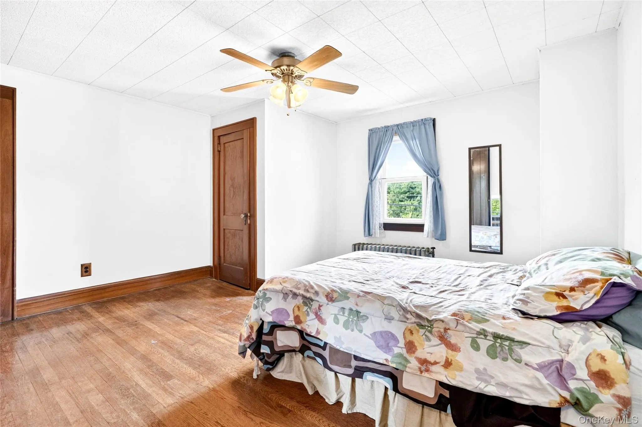 Wood-finish flooring, white walls, wood-finish trim, window with natural light, and a ceiling fan Wood-finish flooring, white walls, wood-finish trim, window with natural light, and a ceiling fan