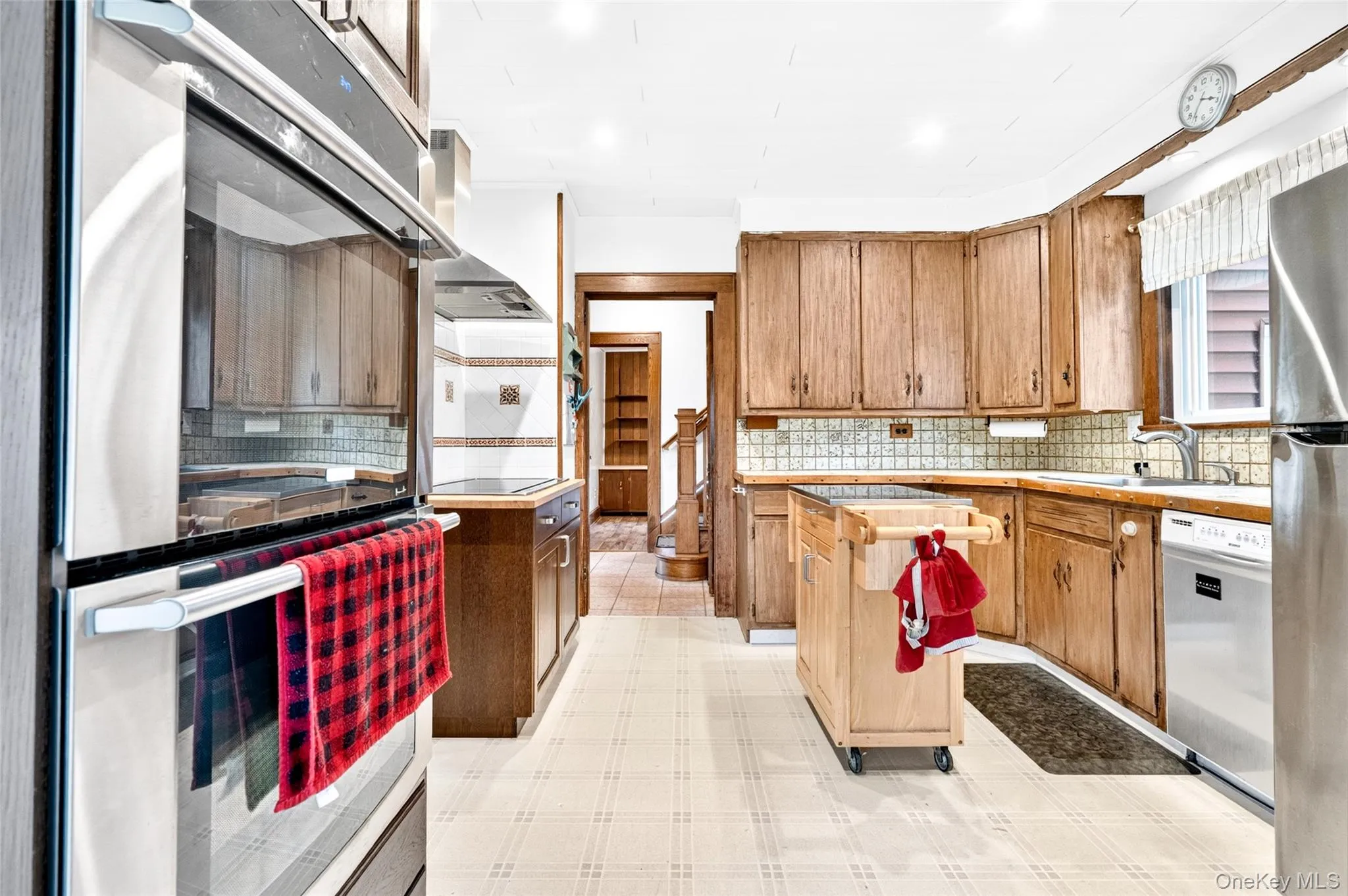 Built-in stainless steel double oven, wood cabinetry, tile backsplash, and stainless steel appliances Built-in stainless steel double oven, wood cabinetry, tile backsplash, and stainless steel appliances