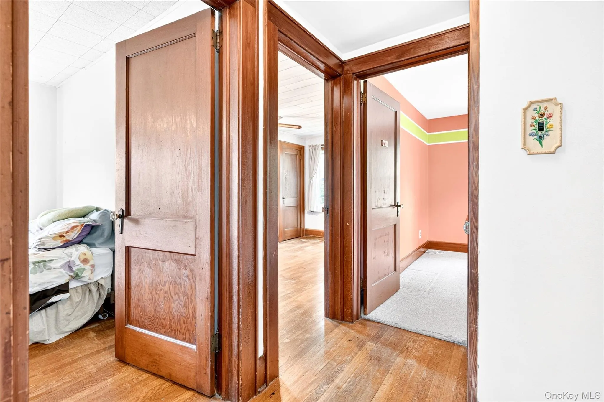 Wood-finish flooring throughout, featuring paneled doors with dark hardware, and light-toned walls Wood-finish flooring throughout, featuring paneled doors with dark hardware, and light-toned walls