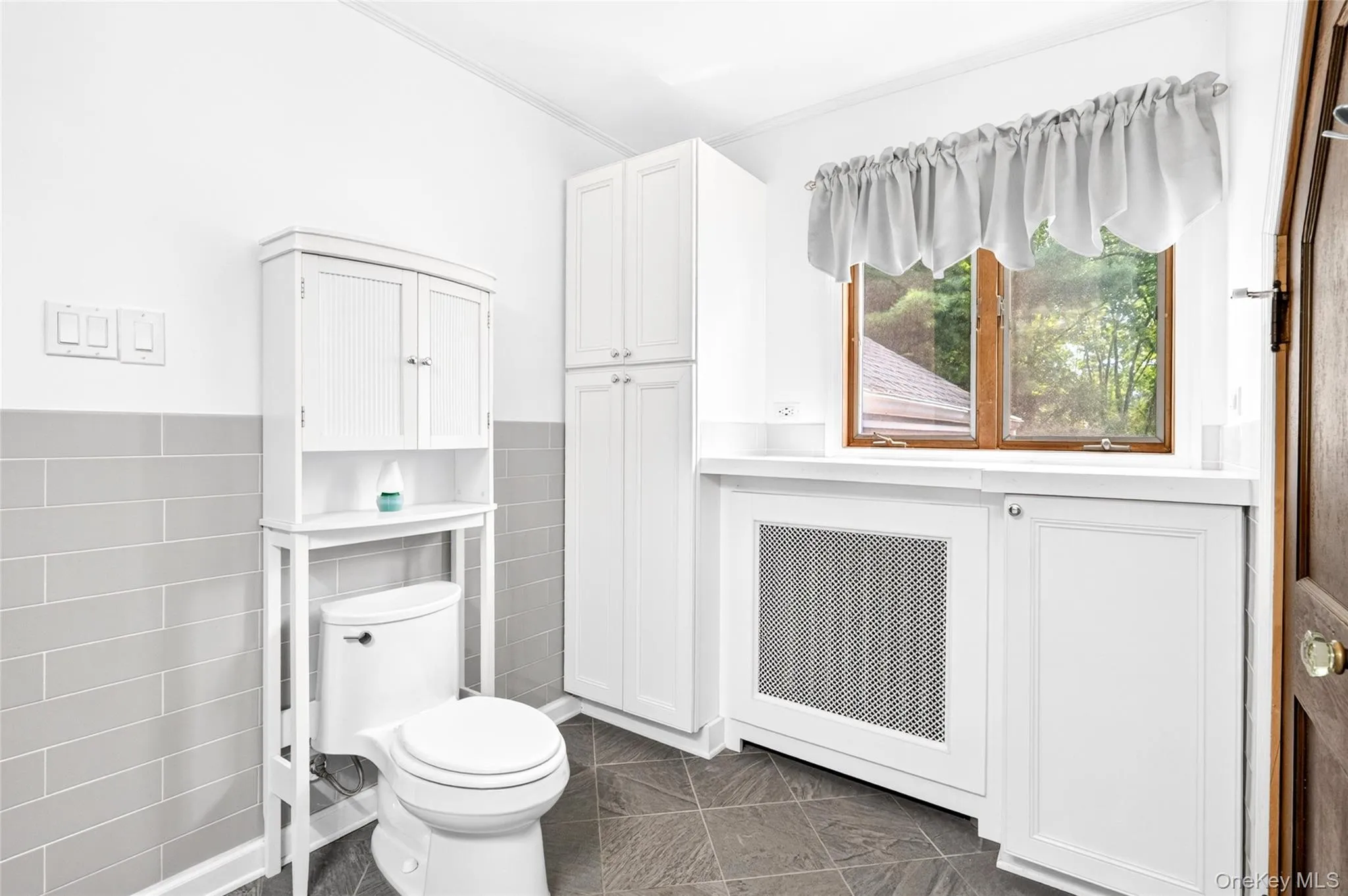White floor-to-ceiling cabinetry, built-in storage with countertop, and gray tiled accent wall White floor-to-ceiling cabinetry, built-in storage with countertop, and gray tiled accent wall