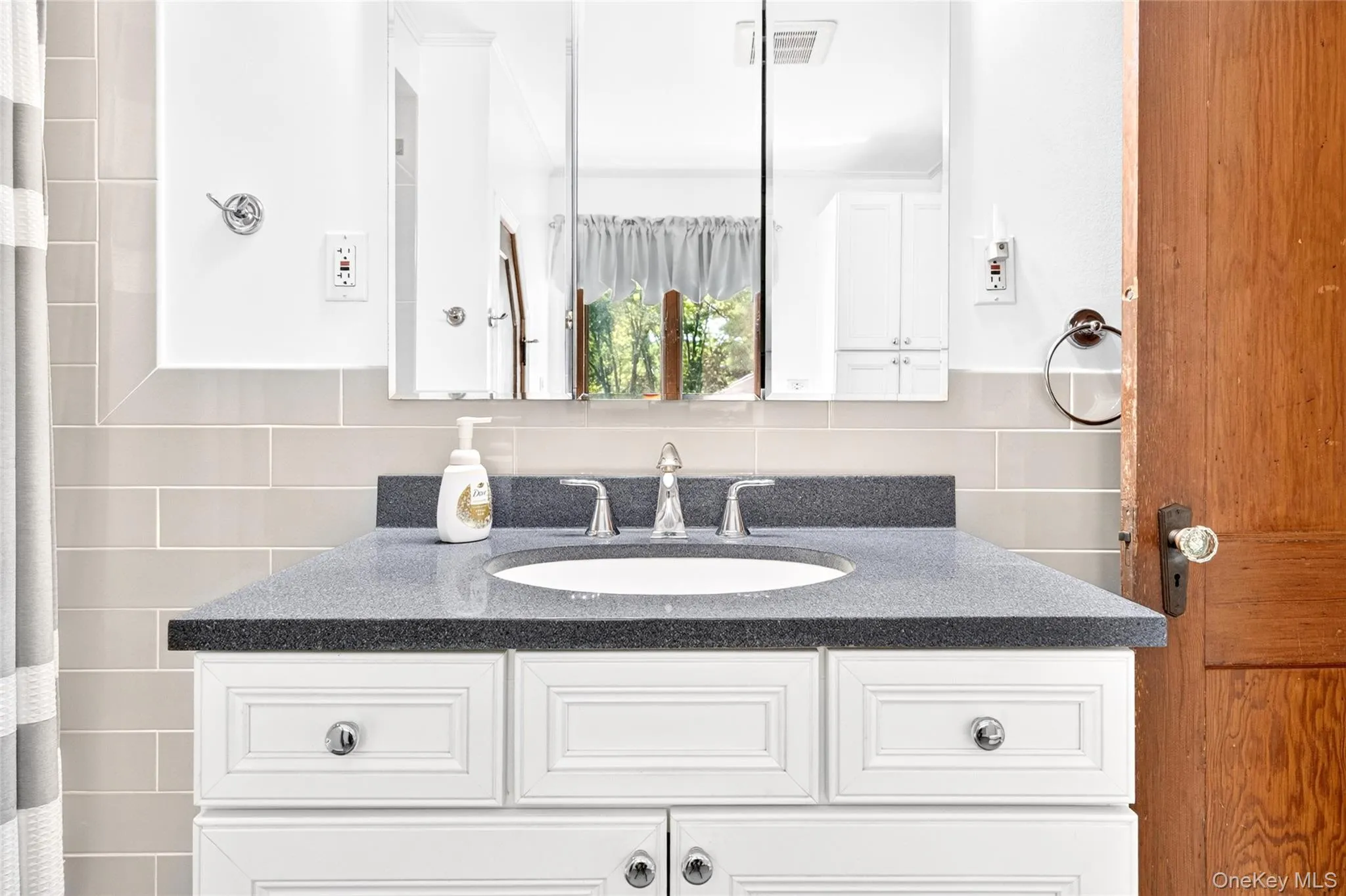 White vanity with paneled doors and drawers, dark solid surface countertop, undermount sink, and chrome faucet White vanity with paneled doors and drawers, dark solid surface countertop, undermount sink, and chrome faucet