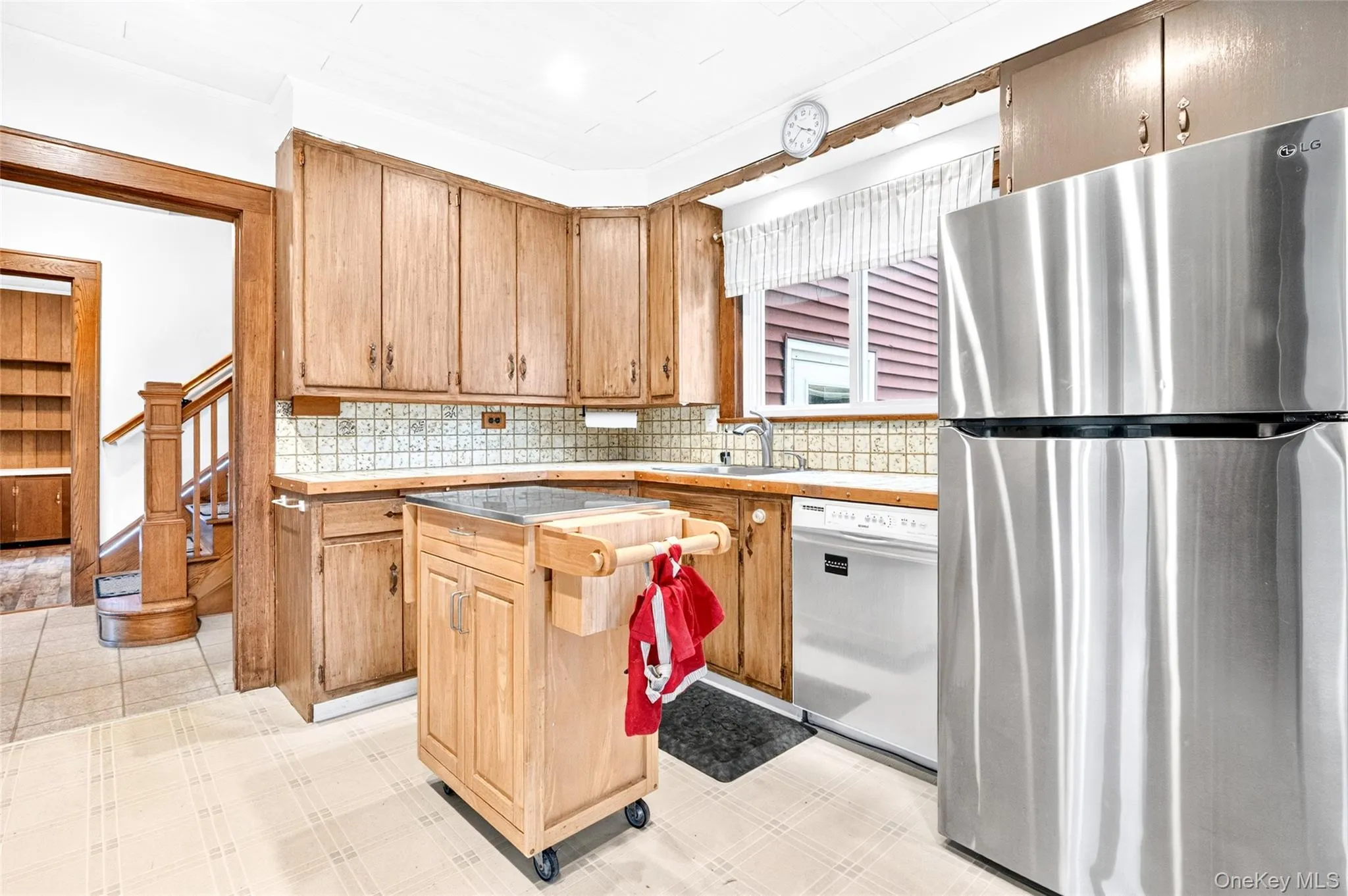 Kitchen with wood-finish cabinetry, tile backsplash, and stainless steel refrigerator Kitchen with wood-finish cabinetry, tile backsplash, and stainless steel refrigerator