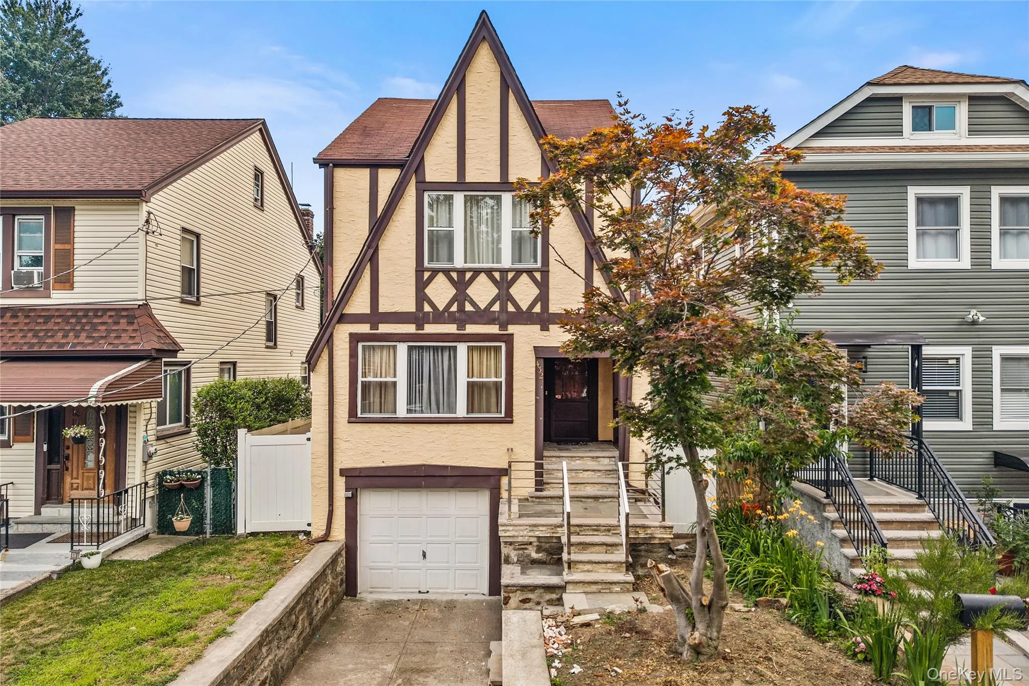 Tudor-style facade featuring prominent gables, decorative half-timbering, a single-car garage, and an elevated stone stairway approach to the entry Tudor-style facade featuring prominent gables, decorative half-timbering, a single-car garage, and an elevated stone stairway approach to the entry