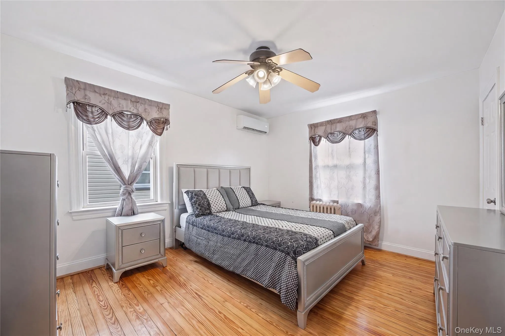 Hardwood flooring throughout featuring white walls, a ceiling fan with integrated lighting, and white trim Hardwood flooring throughout featuring white walls, a ceiling fan with integrated lighting, and white trim