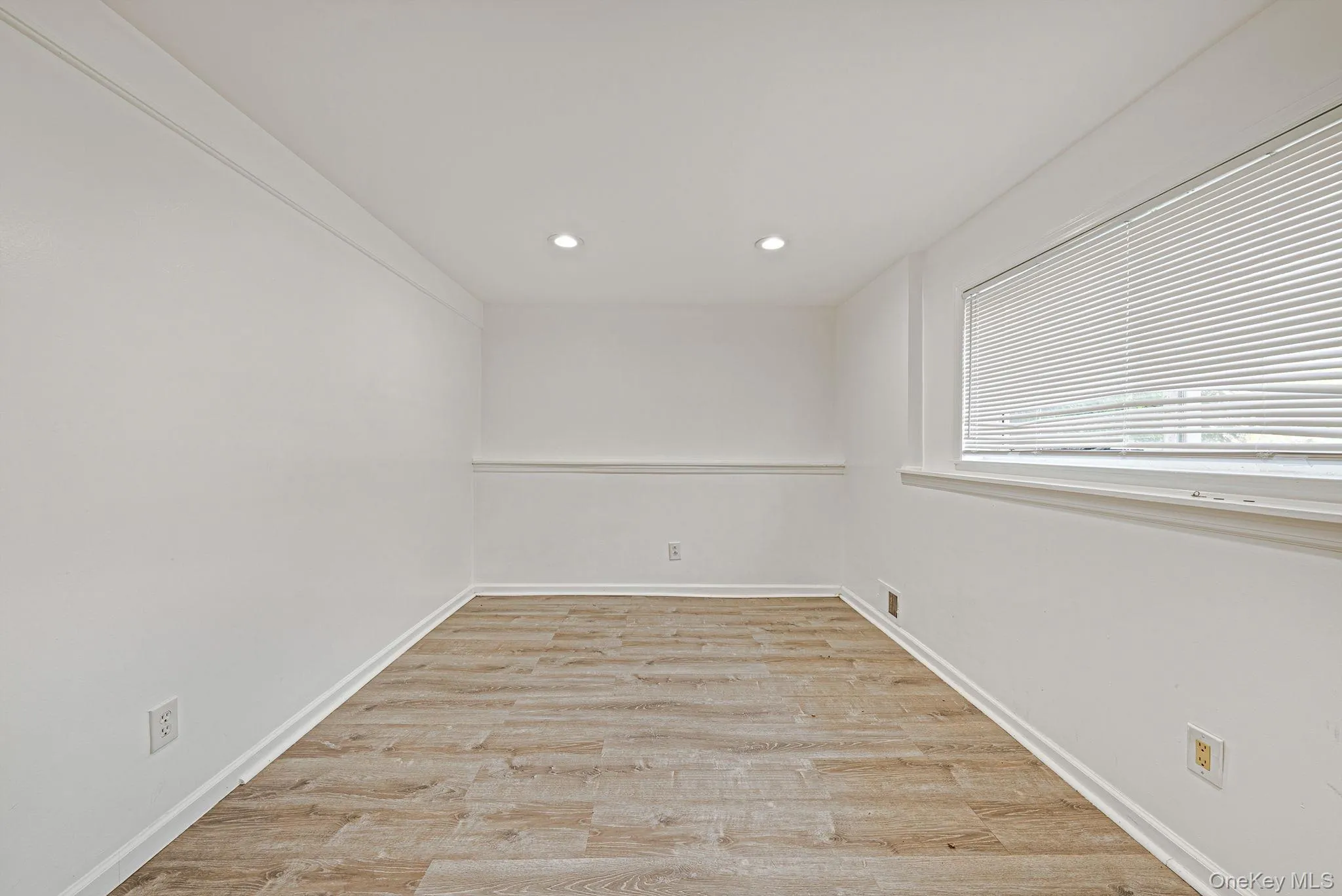 Versatile interior space featuring wood-finish flooring, recessed lighting, and a window with horizontal blinds Versatile interior space featuring wood-finish flooring, recessed lighting, and a window with horizontal blinds