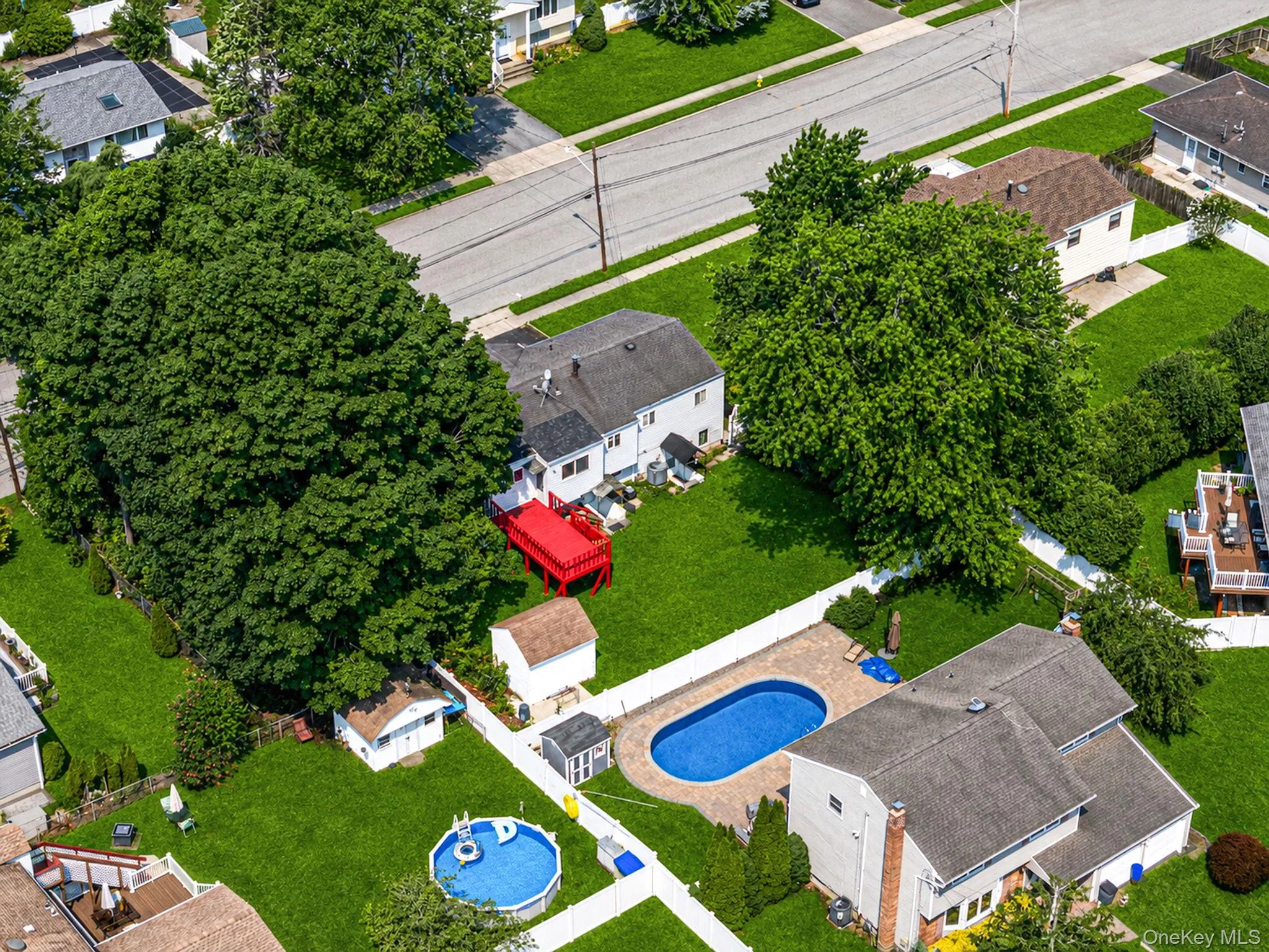Spacious property featuring a large in-ground swimming pool with surrounding patio, expansive manicured lawn, mature trees, and a detached shed Spacious property featuring a large in-ground swimming pool with surrounding patio, expansive manicured lawn, mature trees, and a detached shed