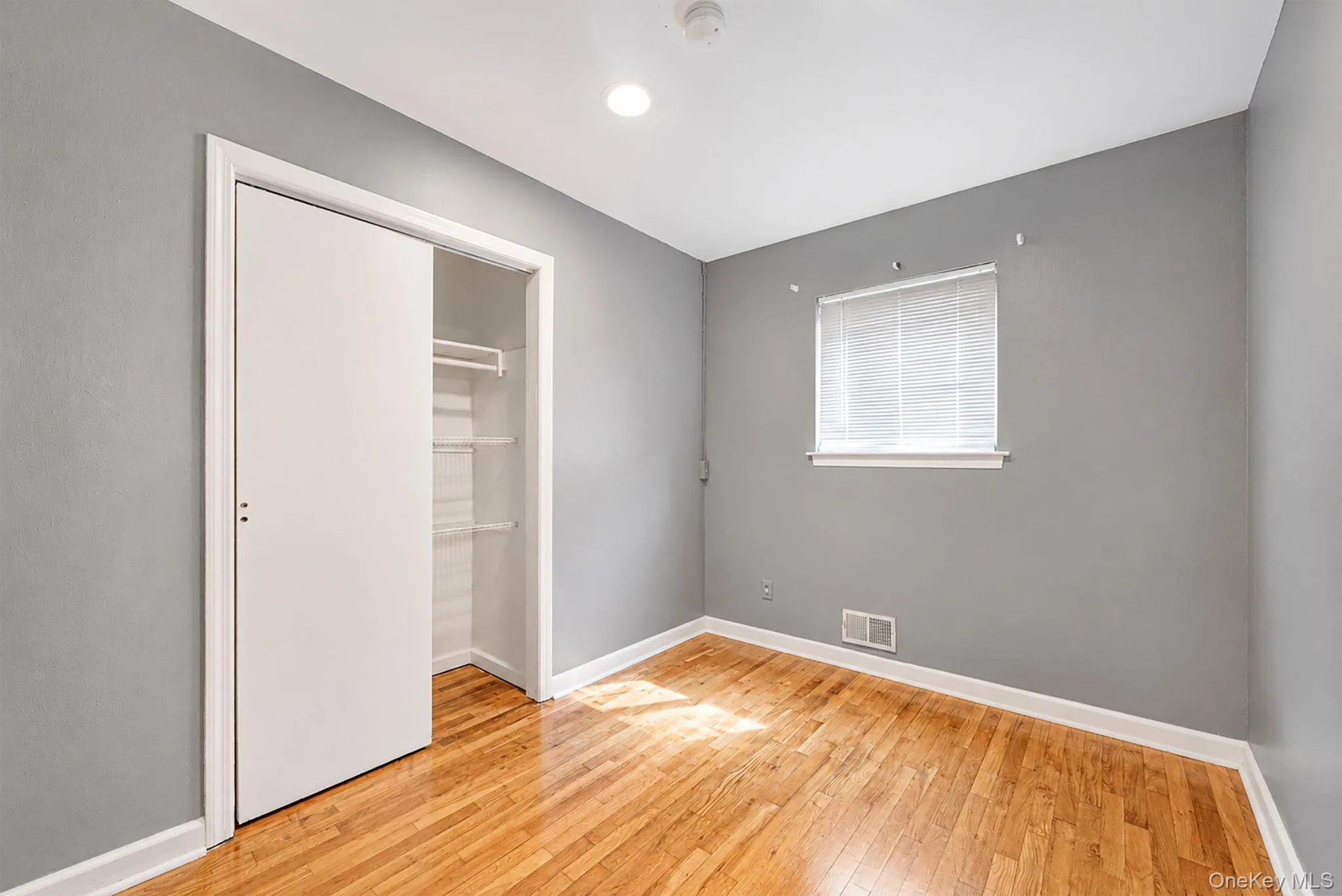 Room featuring wood-finish flooring and a neutral gray wall color Room featuring wood-finish flooring and a neutral gray wall color