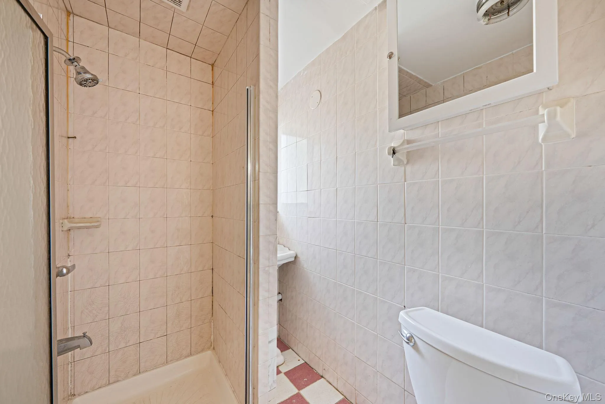 Shower stall with a glass enclosure, white tile surround, and a chrome shower head Shower stall with a glass enclosure, white tile surround, and a chrome shower head