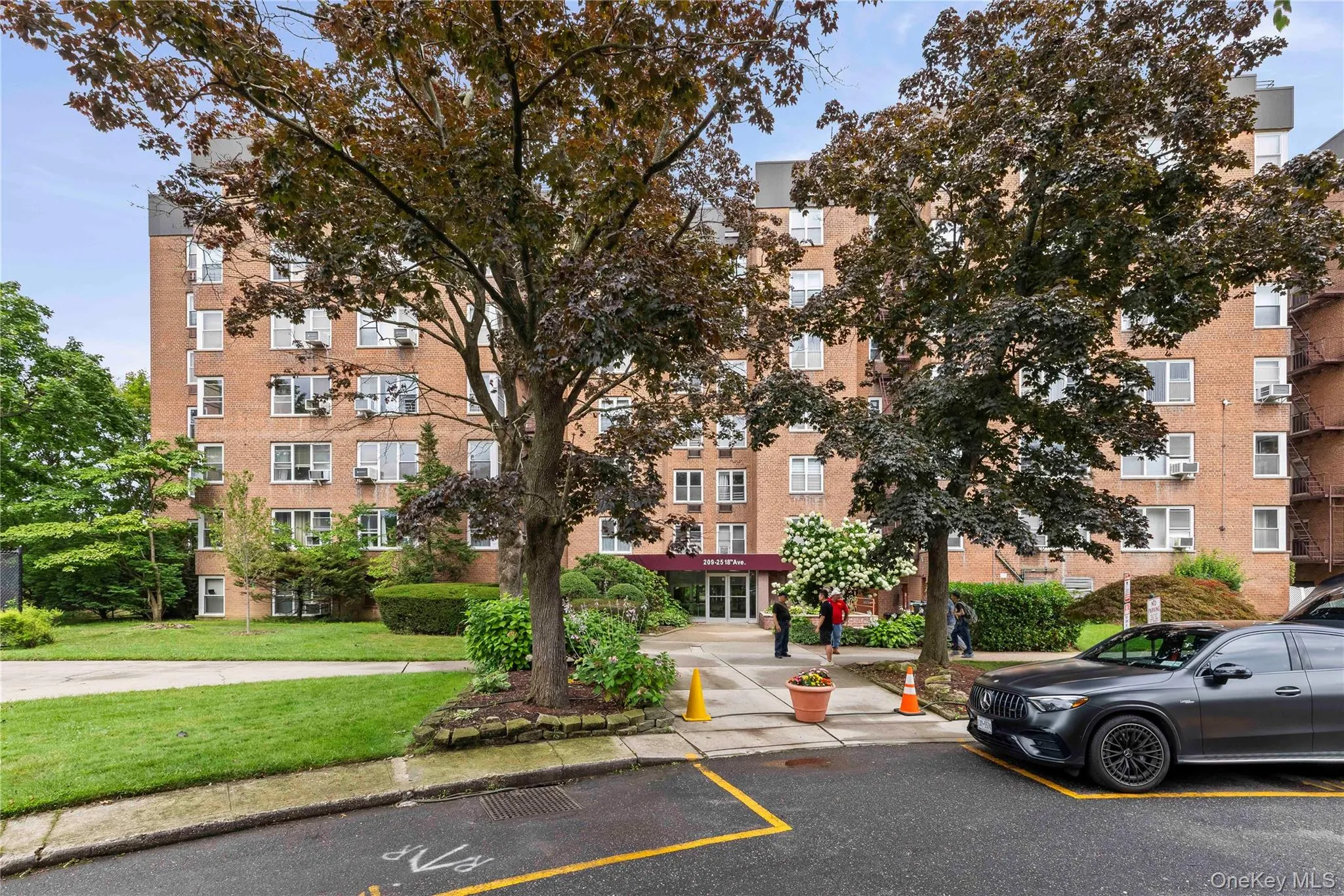 Brick apartment building with multiple windows, featuring a prominent entrance with a red awning Brick apartment building with multiple windows, featuring a prominent entrance with a red awning