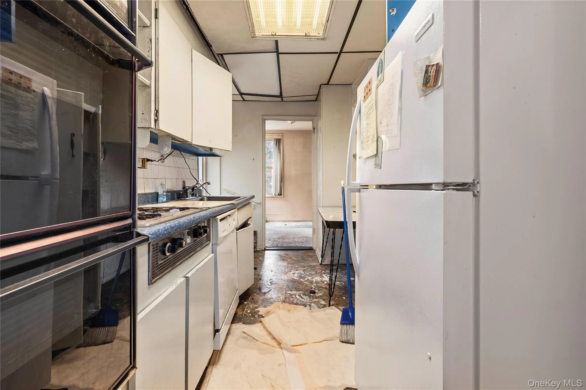 Galley kitchen featuring white cabinetry, a built-in oven, a cooktop, and a dishwasher Galley kitchen featuring white cabinetry, a built-in oven, a cooktop, and a dishwasher