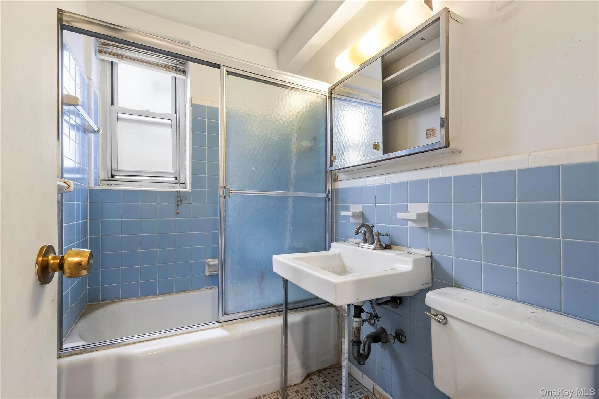 Bright, updated bathroom featuring blue tile walls, a frameless glass shower enclosure with chrome fixtures, a white pedestal sink, and ample natural light from the window Bright, updated bathroom featuring blue tile walls, a frameless glass shower enclosure with chrome fixtures, a white pedestal sink, and ample natural light from the window