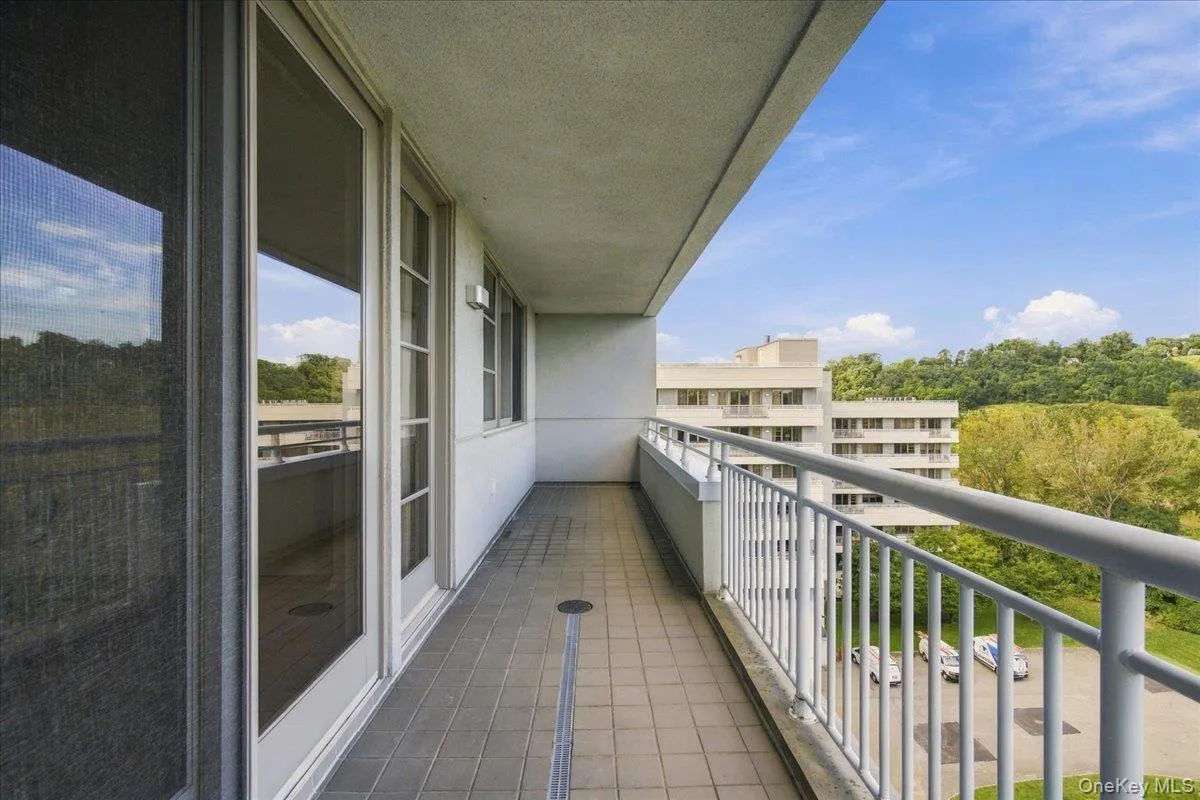 Tiled balcony with a white metal railing and a sliding glass door Tiled balcony with a white metal railing and a sliding glass door
