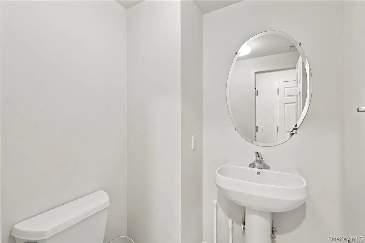 Pedestal sink, wall-mounted oval mirror, and white toilet Pedestal sink, wall-mounted oval mirror, and white toilet