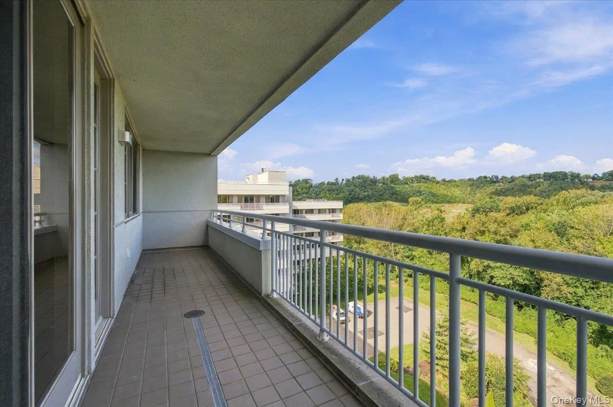 Balcony featuring tile flooring, a metal railing, and a verdant landscape backdrop Balcony featuring tile flooring, a metal railing, and a verdant landscape backdrop