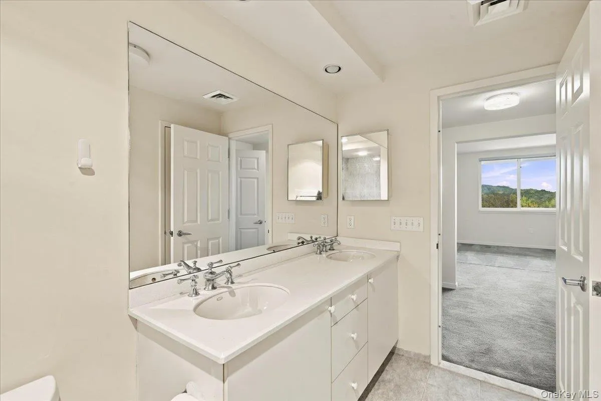 Dual vanity with integrated sinks and chrome fixtures, framed by a large wall mirror Dual vanity with integrated sinks and chrome fixtures, framed by a large wall mirror