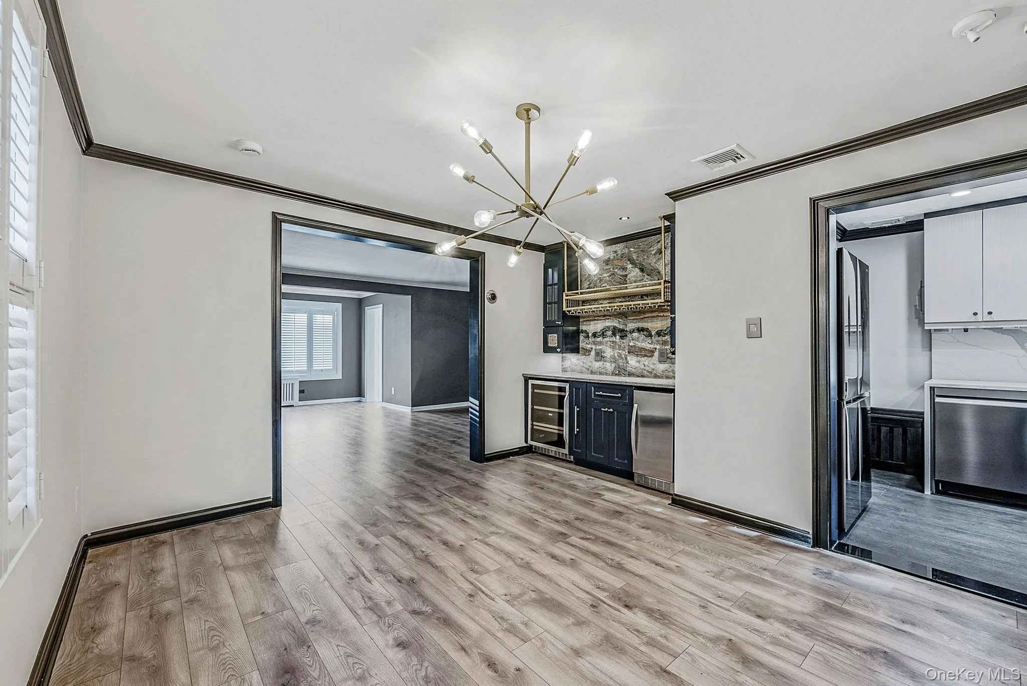 Kitchen with ornamental molding, stainless steel appliances, backsplash, glass insert cabinets, and light wood-style flooring Kitchen with ornamental molding, stainless steel appliances, backsplash, glass insert cabinets, and light wood-style flooring