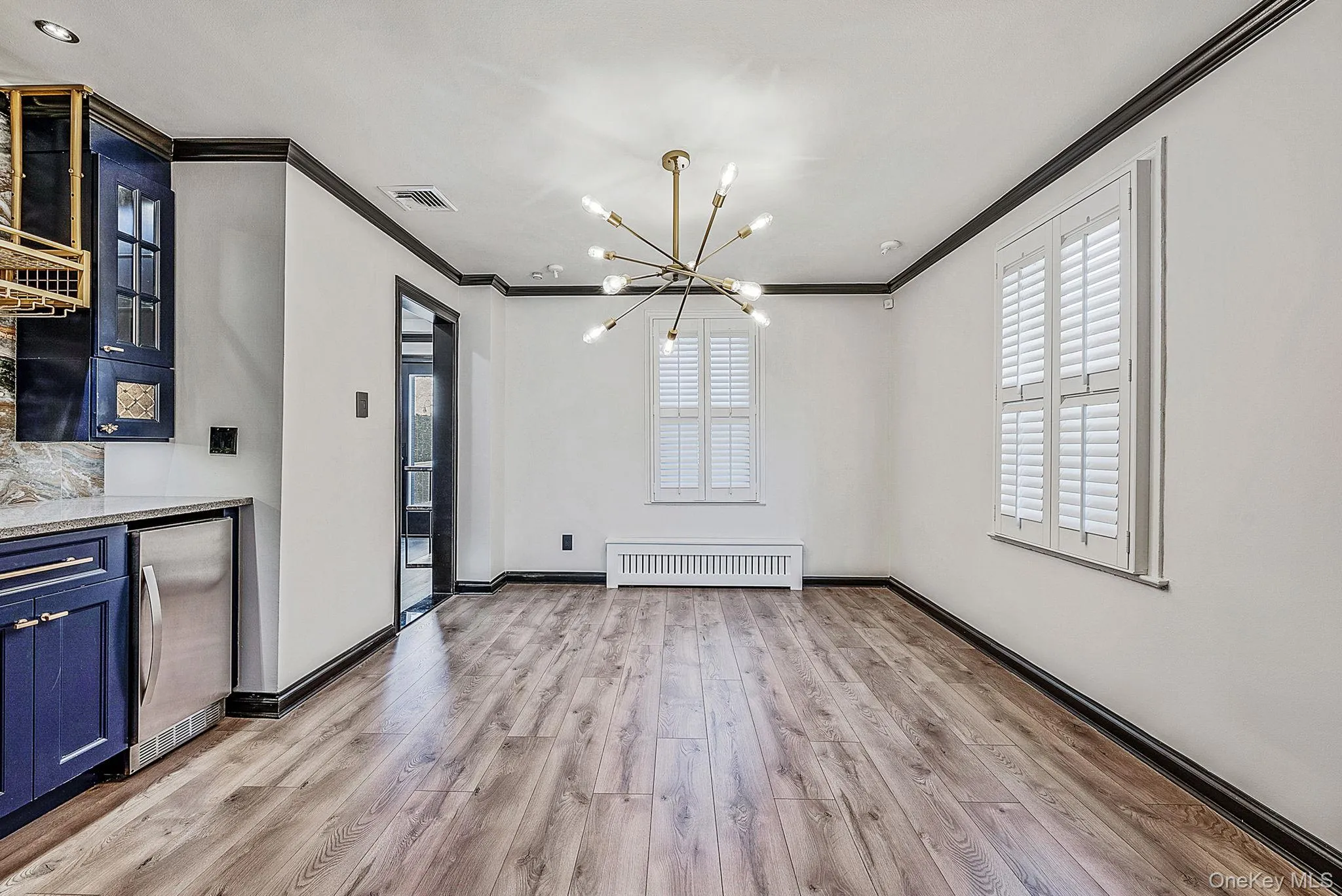 Unfurnished dining area featuring a chandelier, ornamental molding, light wood-style flooring, and radiator Unfurnished dining area featuring a chandelier, ornamental molding, light wood-style flooring, and radiator