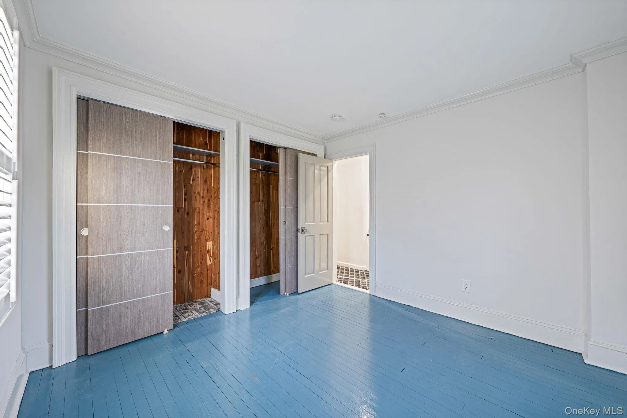 Unfurnished bedroom featuring hardwood / wood-style floors, multiple closets, and ornamental molding Unfurnished bedroom featuring hardwood / wood-style floors, multiple closets, and ornamental molding