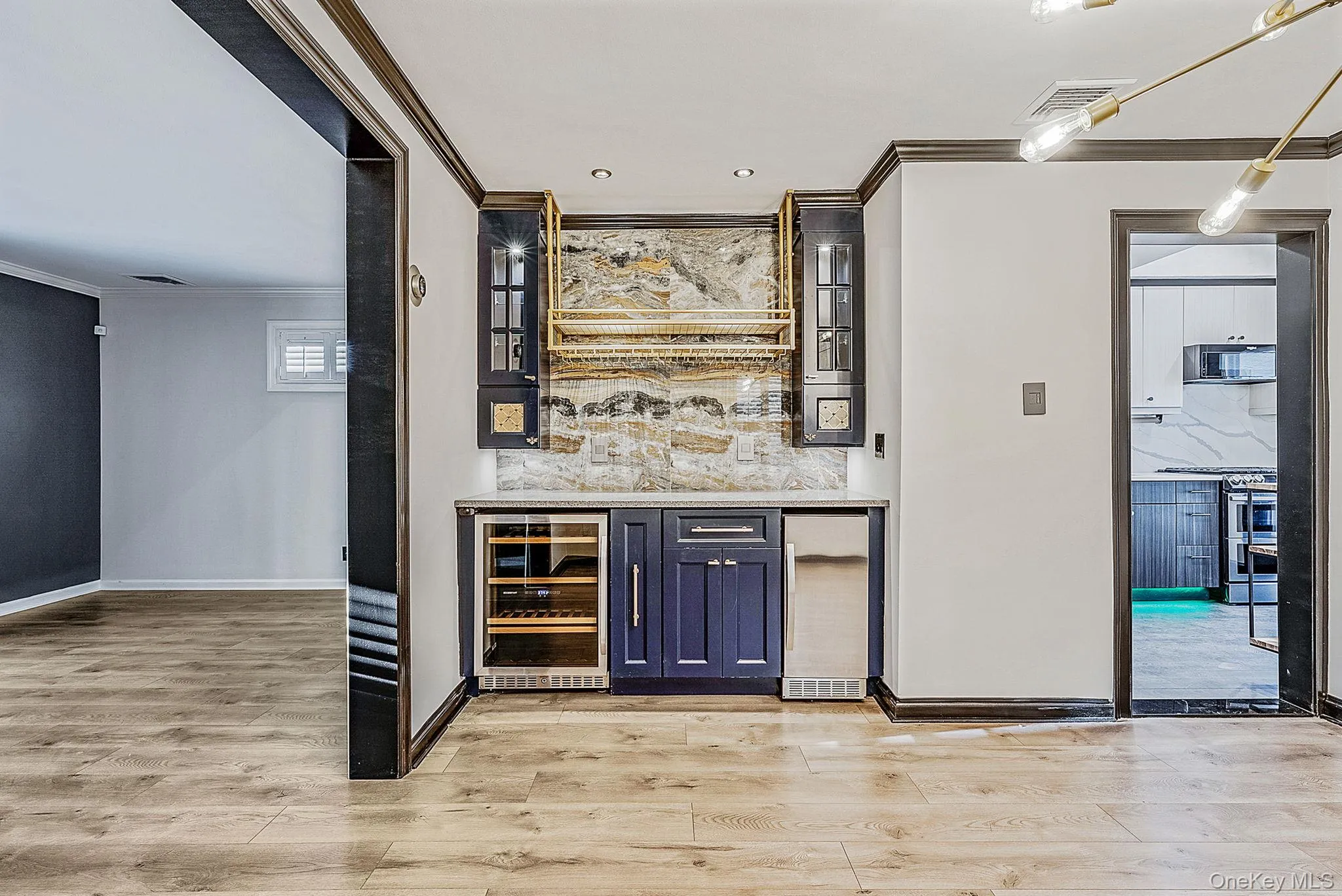 Indoor dry bar with glass insert cabinets, crown molding, wine cooler, light stone counters, and stainless steel range Indoor dry bar with glass insert cabinets, crown molding, wine cooler, light stone counters, and stainless steel range